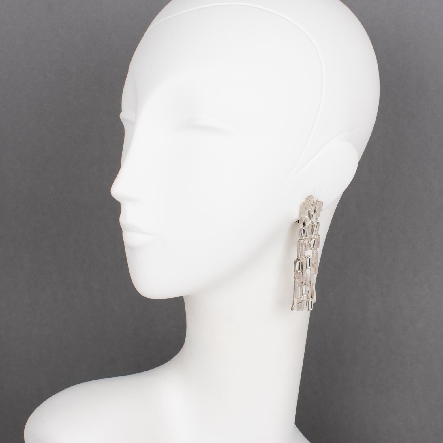 Claude Montana designed these stunning brutalist clip-on earrings for Marie Paris in the 1980s. The pieces boast a silverplate dangling shape with carving and a see-thru pattern embellished with baguette-shaped crystal rhinestones. Each piece is
