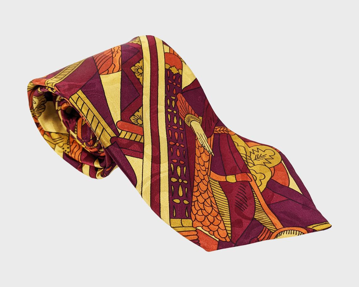 An excellent vintage mens tie from the 80s by legendary French designer, Claude Montana. In a purple, yellow and orange silk with a playing card print throughout featuring the King of Spades and the Queen of Diamonds throughout.

Size: Width -