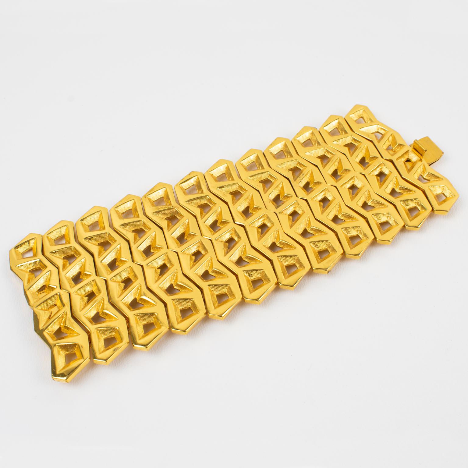 Claude Montana diseñó esta fabulosa pulsera modernista de eslabones geométricos para Marie Paris. La forma importante, futurista, tallada y transparente presenta metal dorado brillante con una textura rayada. La rara pieza lleva el logotipo del