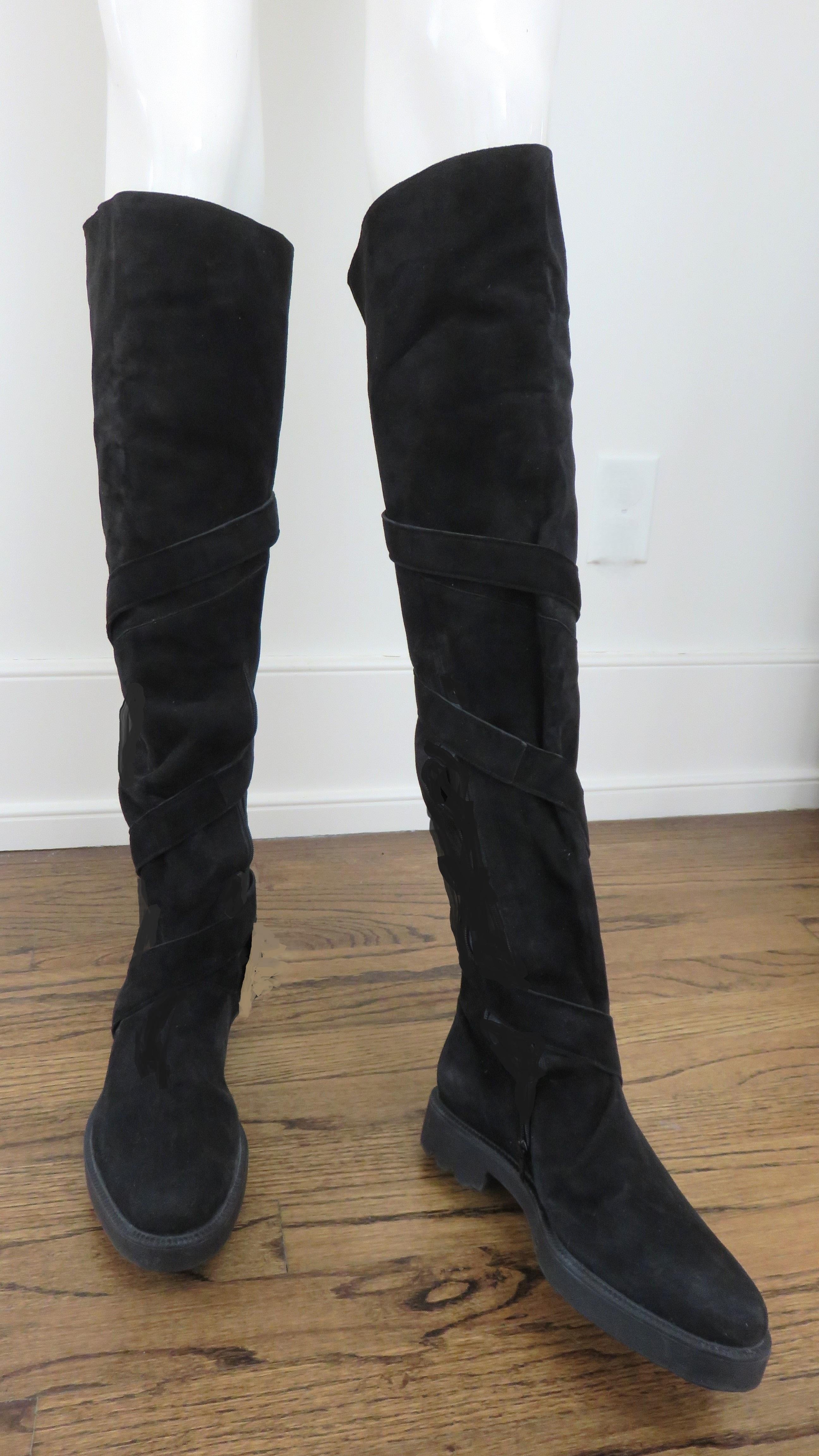 Fabulous never worn black suede boots by Claude Montana for Stephane Kelian in size 8.5.  They are over the knee high with a strap from the ankle to knee which wraps around the boot several times buckling at the back. They have lug soles, inner