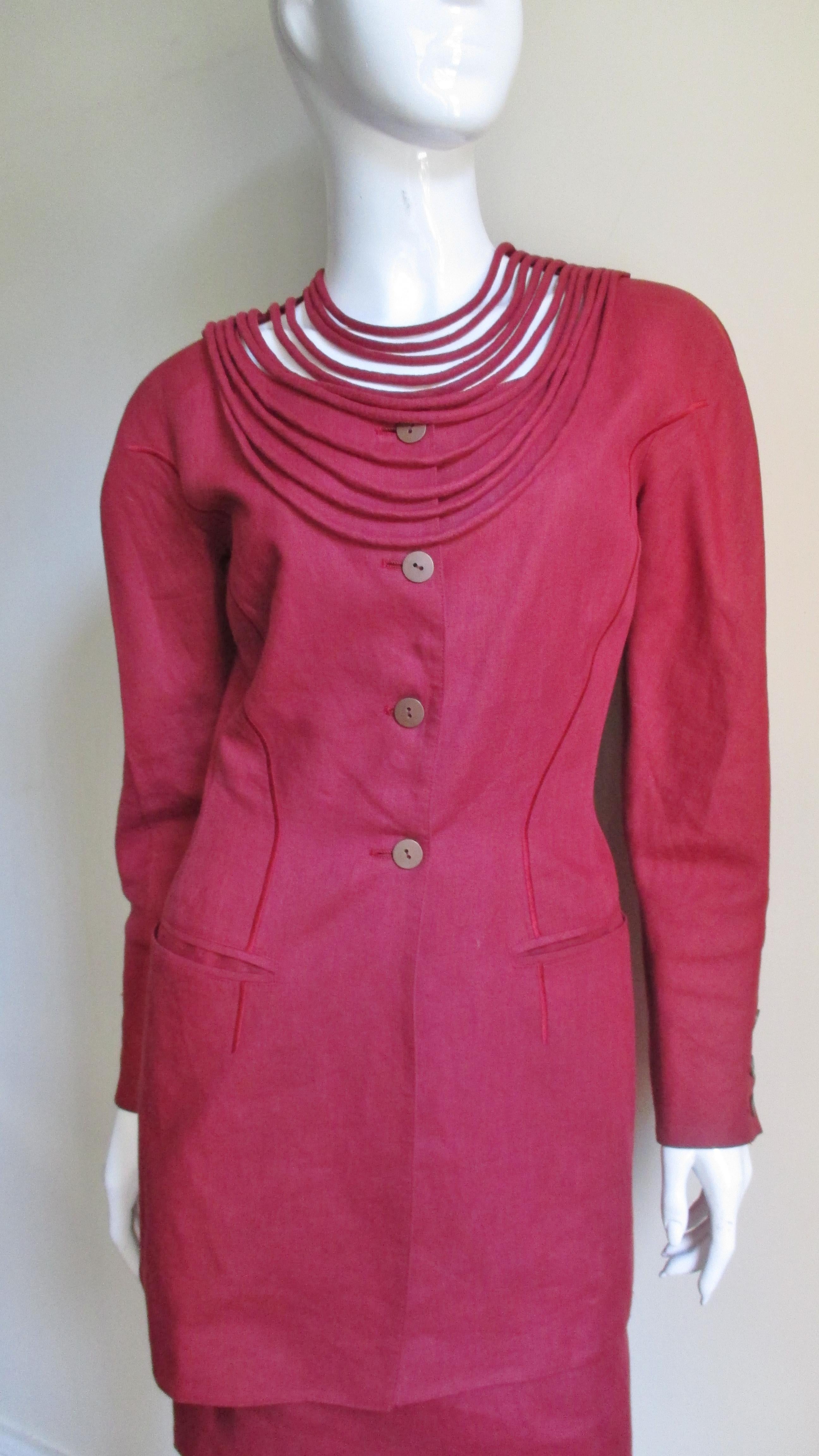 A fabulous deep red linen skirt suit from Claude Montana.  The jacket has lots of fabulous detail including rows of finely piped fabric draping like necklaces at the front neck.  It has shoulder padding, princess seaming, welt pockets and buttons at