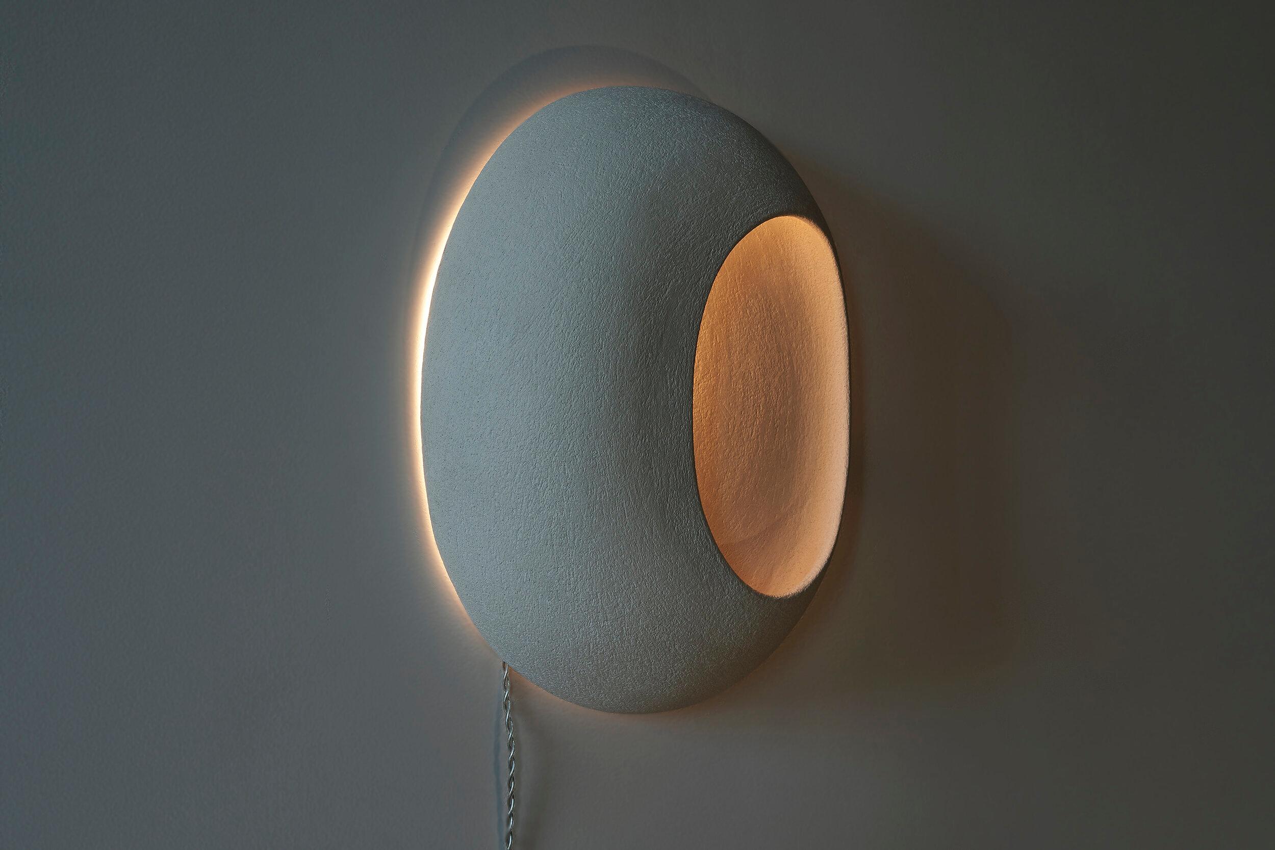 Head in the stars and feet firmly anchored on the ground to stay connected with the universe Eclipse  wall sconces, part of the Cosmos series. Crafted from white sandstone, these sconces evoke the celestial beauty of an eclipse, where light and