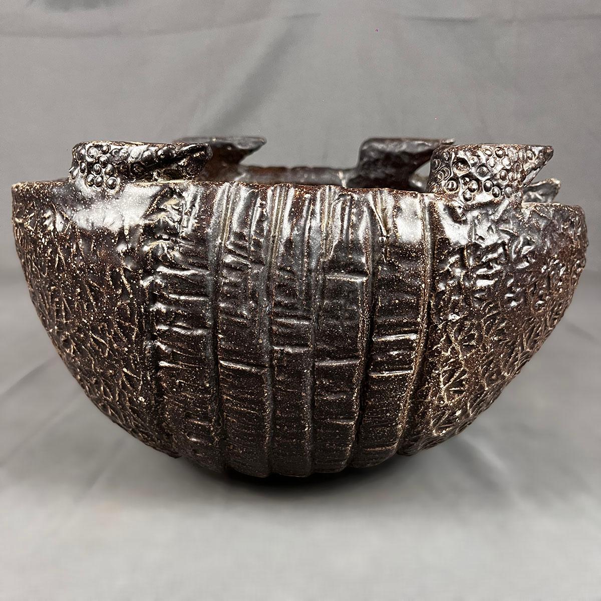 Vaso in ceramica marrone ad alta temperatura a forma di armadillo del ceramista messicano Claudio Jerónimo. Il vaso di forma ovale presenta al suo interno la testa e la coda dell'armadillo, che ricordano una posizione di autodifesa. L'esterno