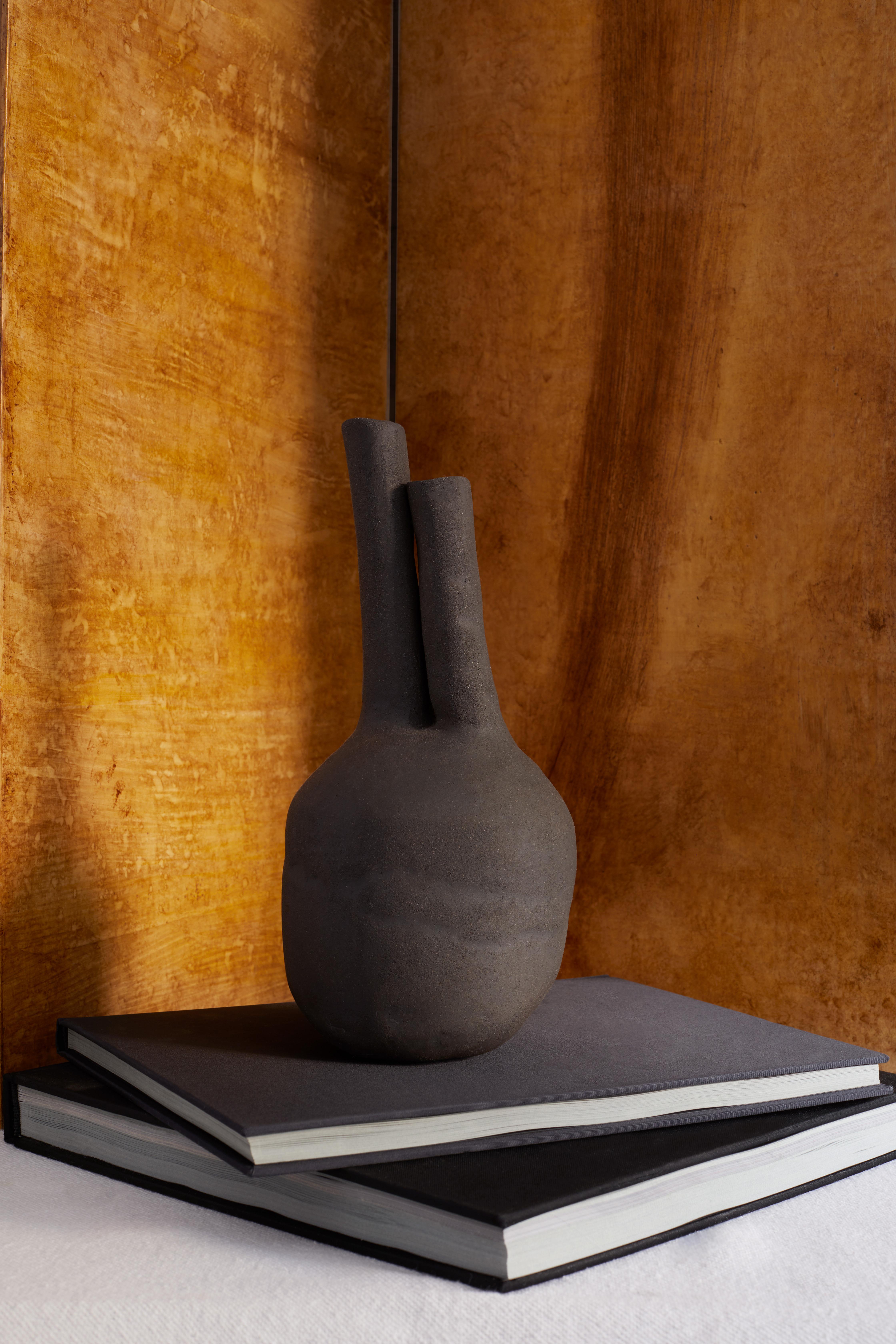 Claudio ist eine Steingutvase mit doppeltem Mund aus der Collection'S Cadaqués, die von der rauen Mittelmeerküste von Cadaqués inspiriert ist. Seine matte, unglasierte Oberfläche erinnert an die natürlichen Strukturen der Küste, wo sich dunkler Sand