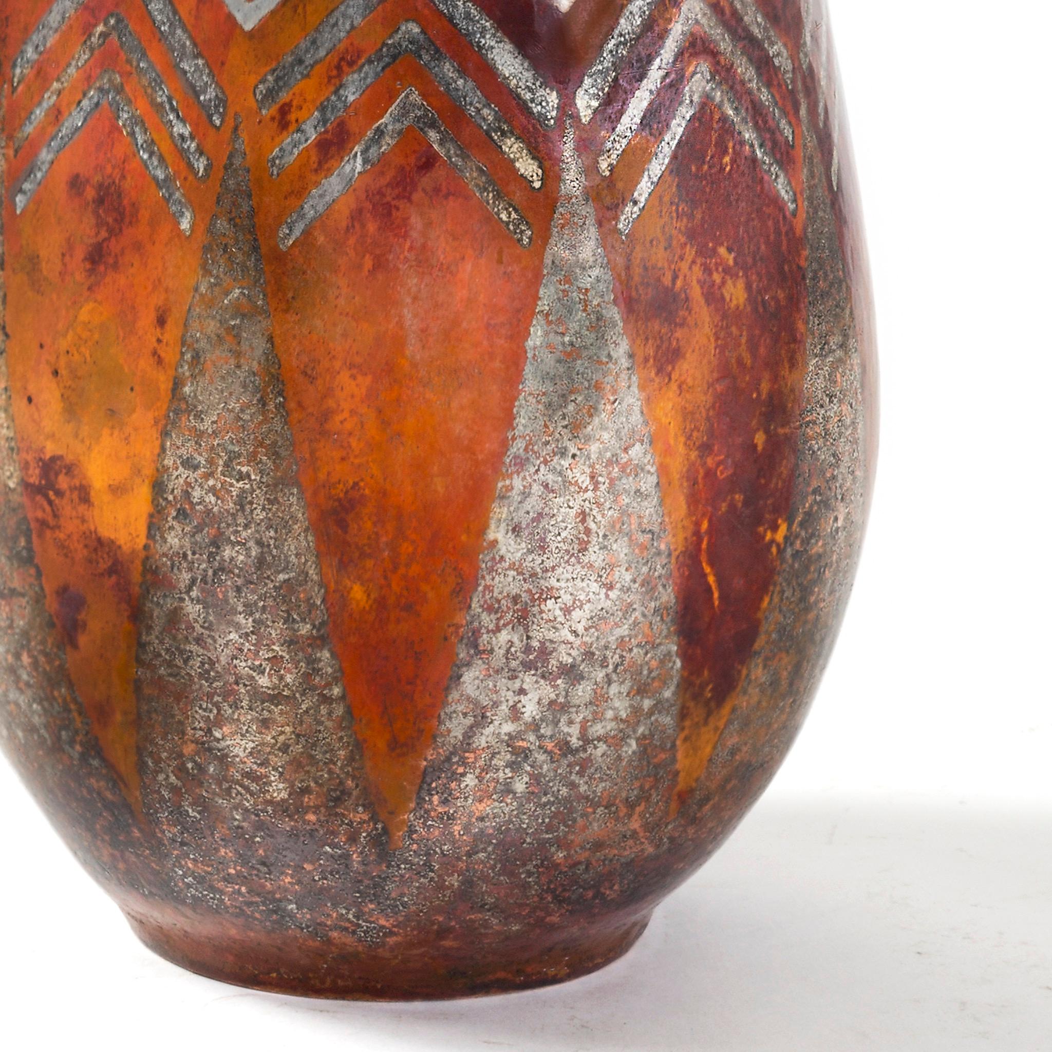 By Claudius Linossier, this French Art Deco mixed metal dinanderie vase is composed of a rich earthen color ground that features a boldly decorative geometric pattern of alternating triangles and diamonds, circling the neck and the middle of the
