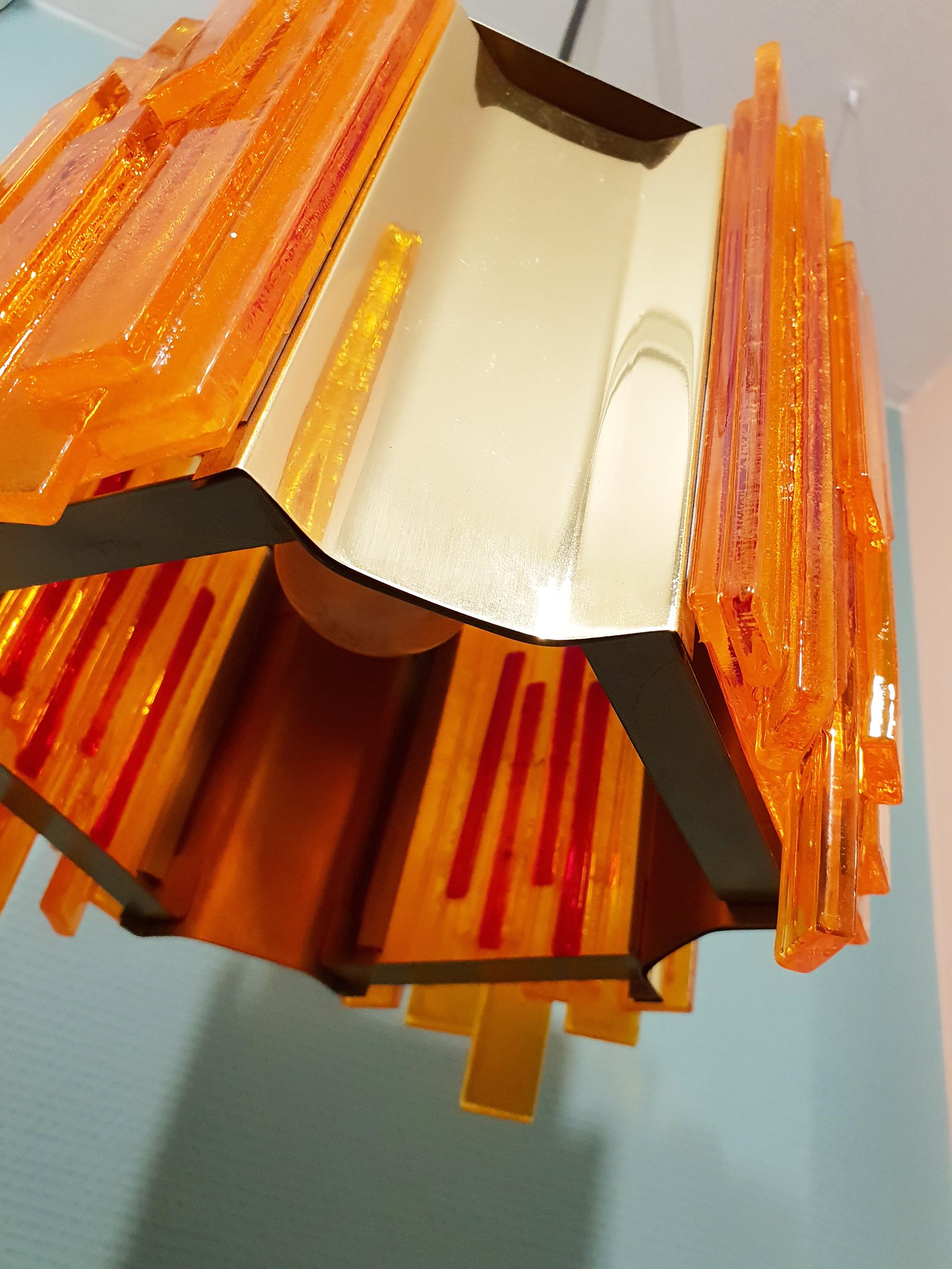 Danish midcentury Scandinavian Modern Space Age octagon shaped pendant designed by Claus Bolby in the 1970s and manufactured by CeBo Industri. 
This lampe has 4 concave brass pieces intermixed with four orange acrylic pieces composed of many