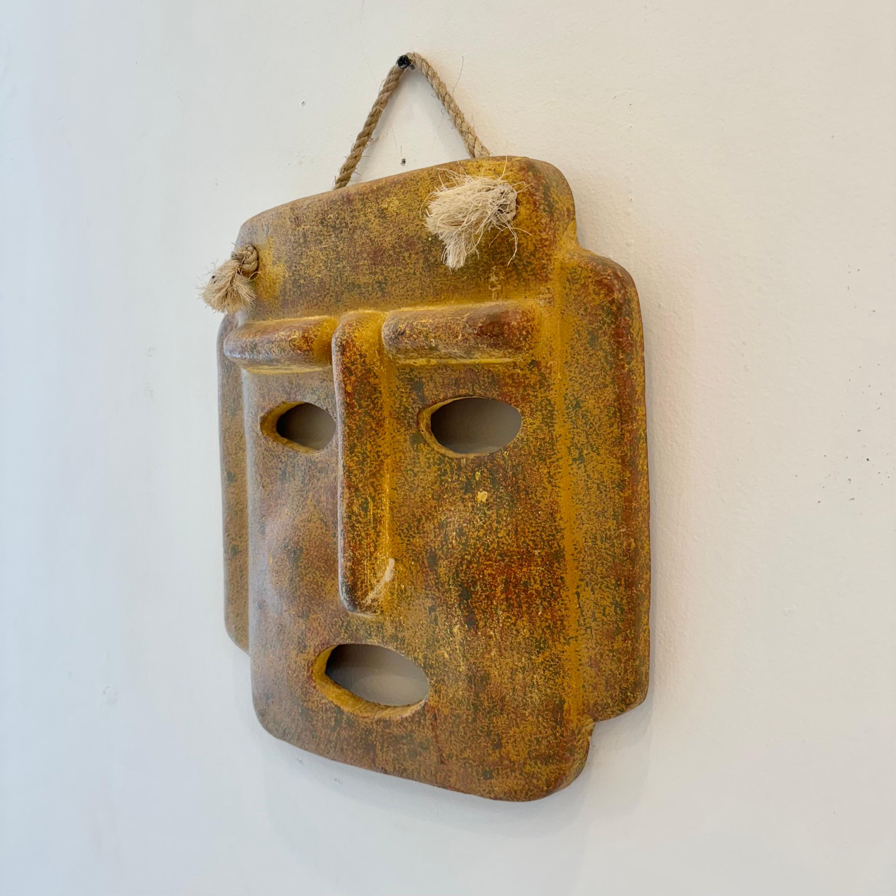 Fantastica maschera scultorea da parete in argilla realizzata in Italia. Realizzata a mano in colore adobe invecchiato con una corda corta che si lega al viso della maschera. Si appende a un'unica vite per semplificare l'installazione. Splendida