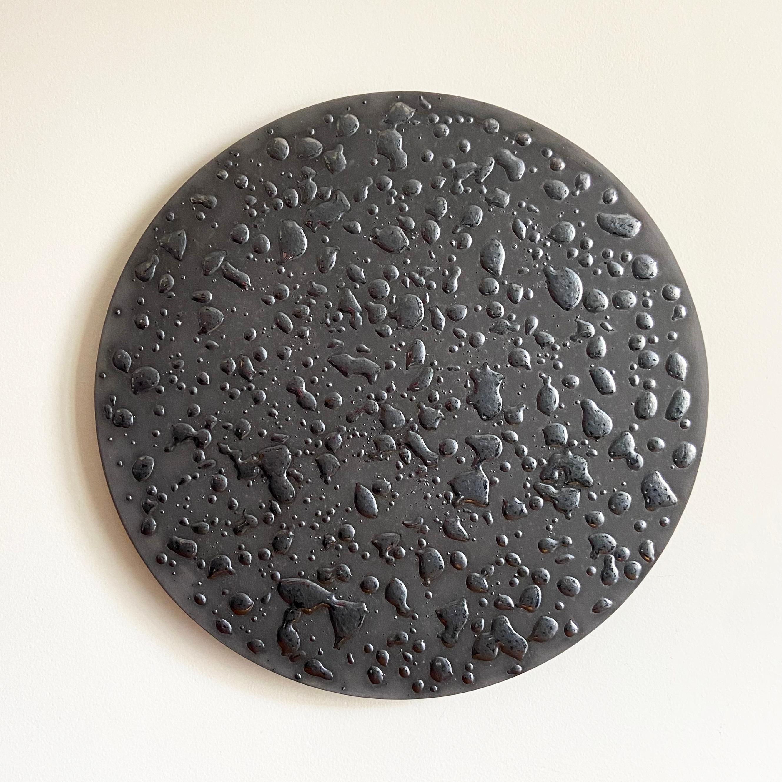 This is a “Clay Painting”, created by Olivia Barry / By Hand.

Black tinted clay with raised, dimensional metallic glaze. Photos show the reflection of bright and muted light.

Using large hand-rolled ceramic canvases, Olivia uses tinted clay