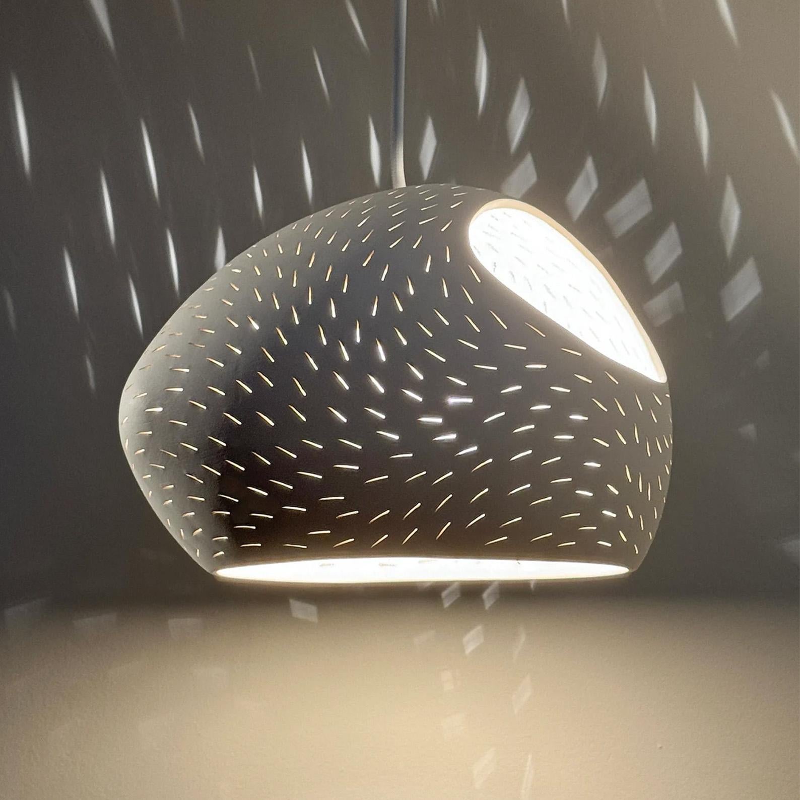 A perforated Egg shaped white ceramic pendant light with two openings, a braided cord and a matching ceiling plate.

The shade is available in two perforation patterns: Line pattern as seen in the front picture and dot pattern as seen in the third