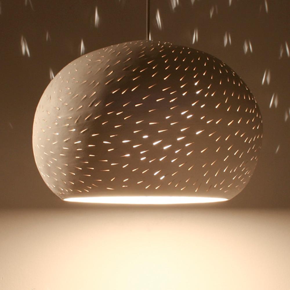 A perforated white ceramic egg shaped symmetrical pendant light with an elegant braided cord and a matching ceramic ceiling plate.

We offer this light in two perforation patterns: Lines or Dots.

Projects light textures on the walls in it's