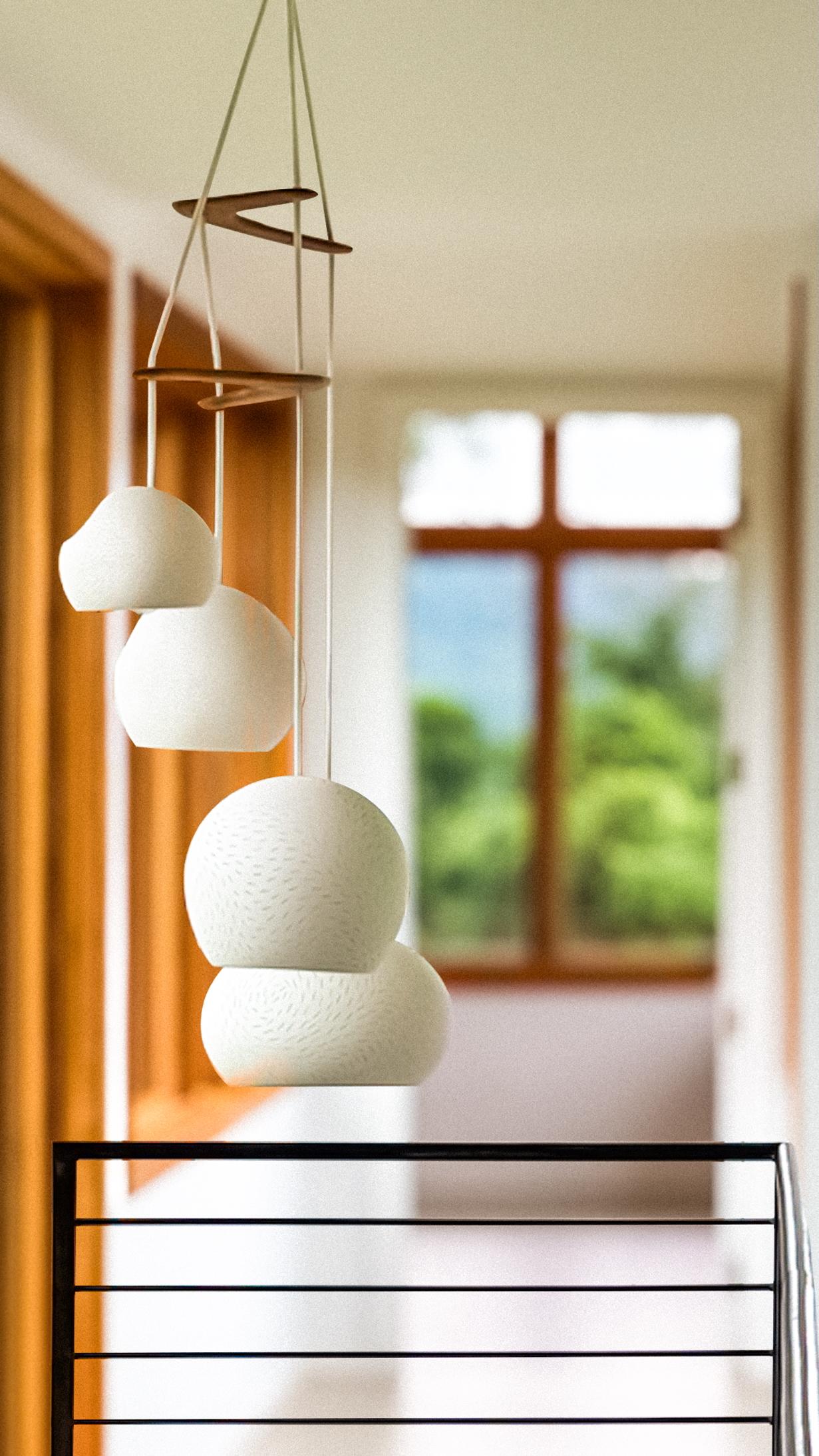 This modern chandelier is a sculptural ceramic lighting statement. The functional design features four matte warm white pendant lamps that hang from Australian brigalow wood, which together create a sculptural mobile of lights, textures, and shapes.