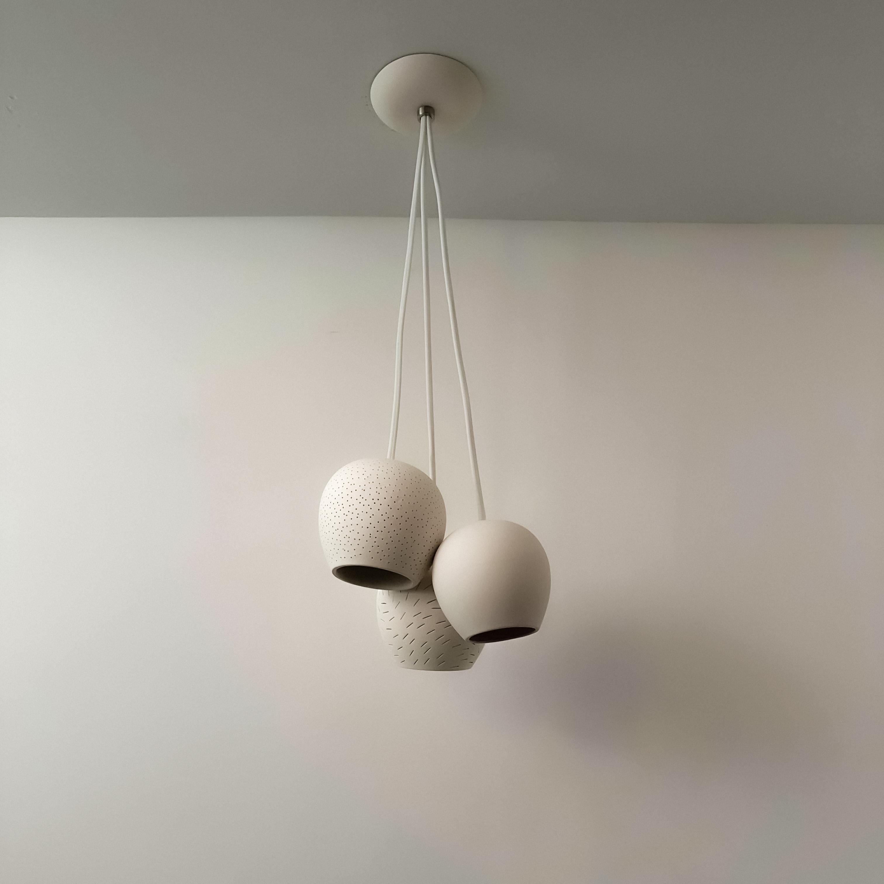 Die Claylight Triplets kombinieren drei unserer Schirmtypen - ein durchscheinendes Porzellan, das bernsteinfarben leuchtet und bei ausgeschaltetem Licht weiß wird, einen warmweißen Keramikschirm mit Punktmuster und einen warmweißen Keramikschirm mit