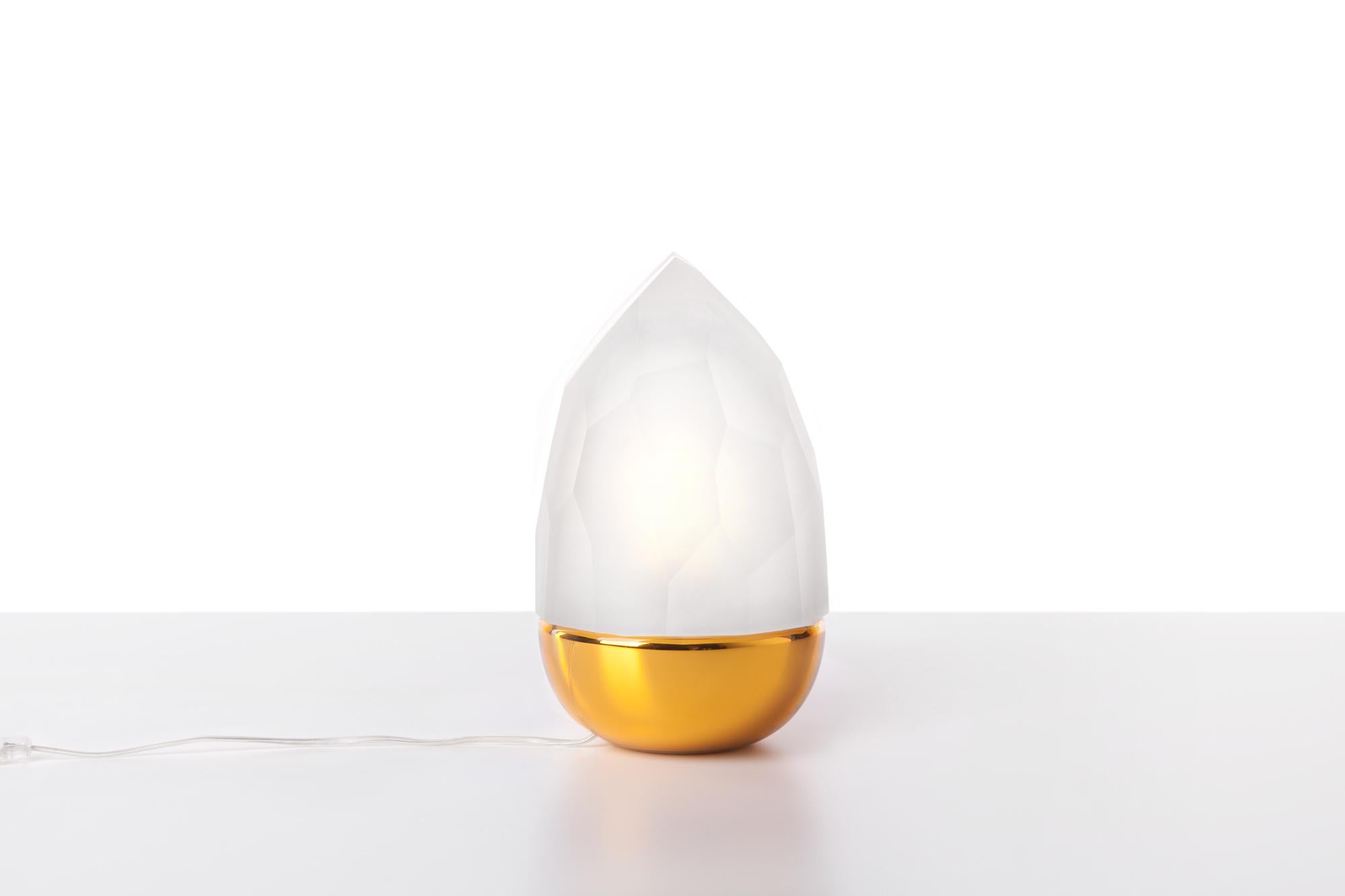 Clear and gold Mr. Flame table lamp by Dechem Studio.
Dimensions: D 18 x H 28 cm.
Materials: glass.
Also available: different colors available.

Two completely contrasting and differently manufactured glass shapes create Mr. Flame Table Lamp.