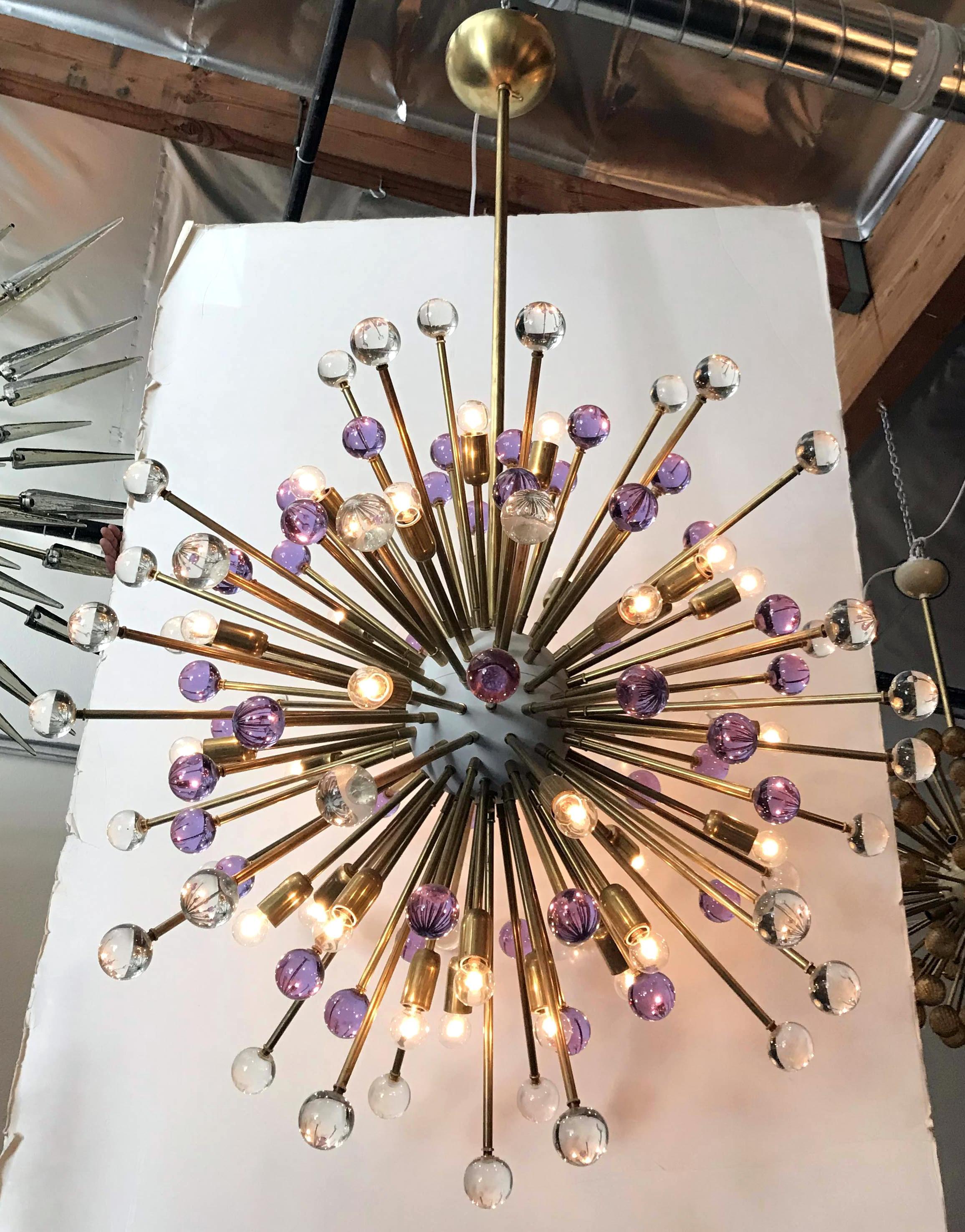 Lustre Sputnik moderne italien avec des sphères en verre de Murano clair et lilas soufflées à la main, montées sur des cadres en laiton naturel avec centre émaillé blanc / Design by Fabio Bergomi for Fabio Ltd / Made in Italy
30 lampes / type E12 ou