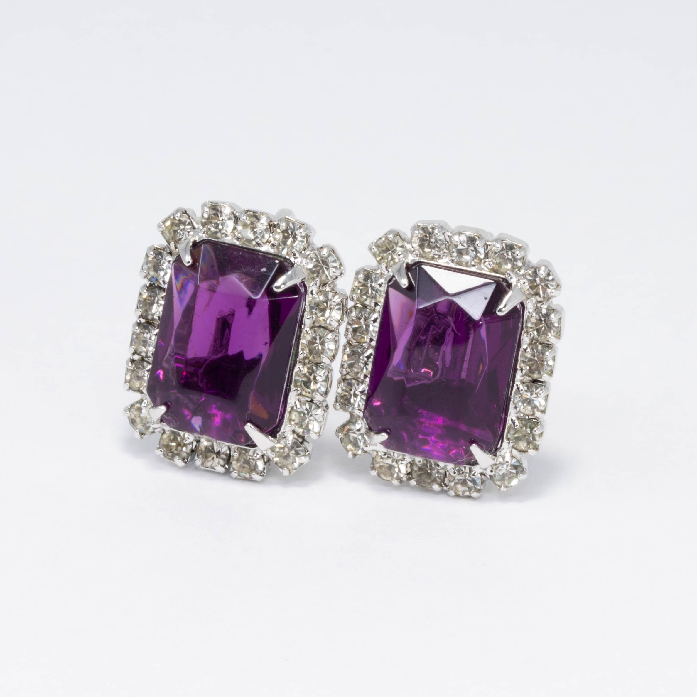 A pair of dazzling vintage clip on earrings. Vibrant amethyst colored crystals are prong set in the center, decorated around with sparkling clear crystals. Silvertone metal, open backs.

