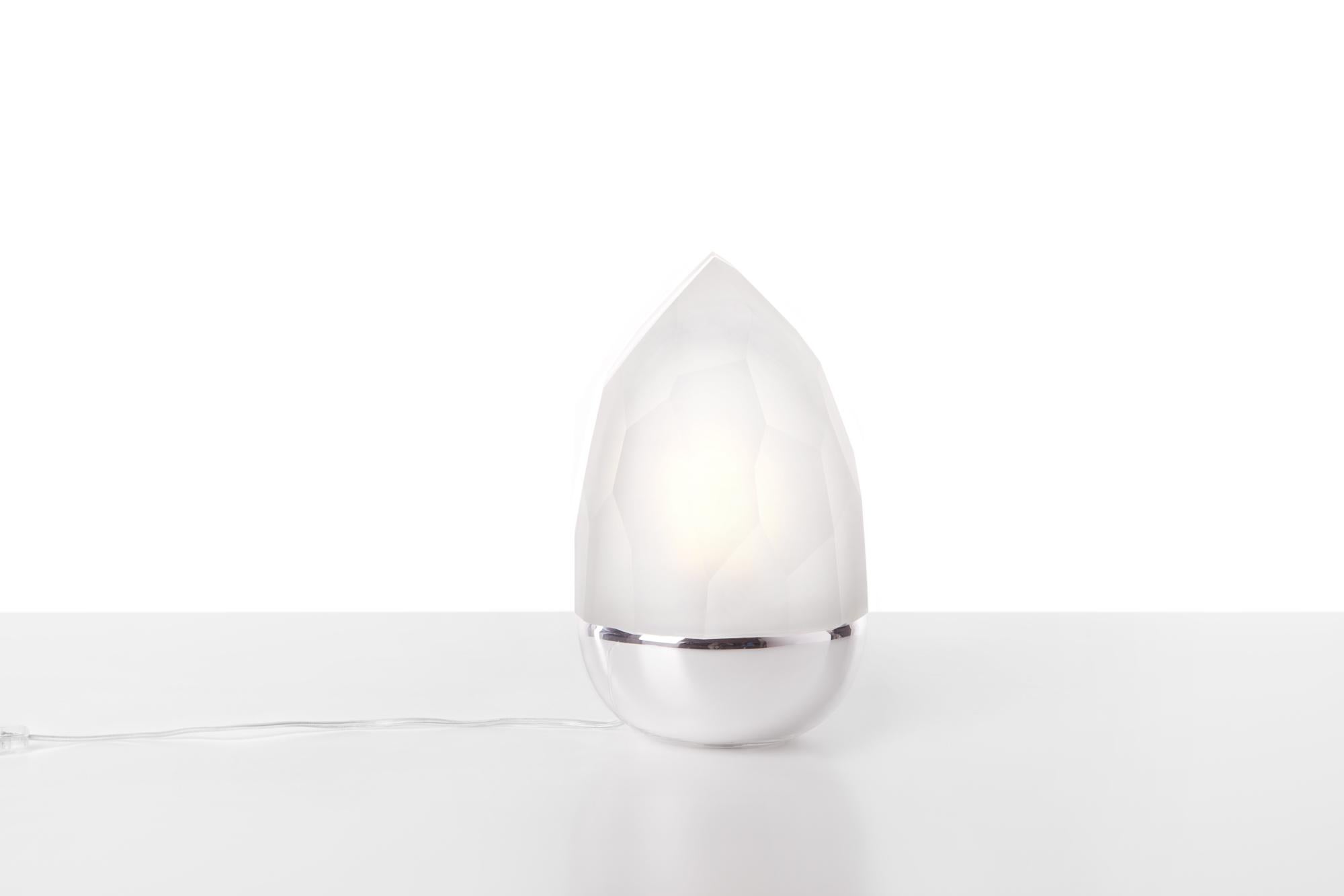 Clear and silver Mr. Flame table lamp by Dechem Studio.
Dimensions: D 18 x H 28 cm.
Materials: glass.
Also available: different colours available.

Two completely contrasting and differently manufactured glass shapes create Mr. Flame Table