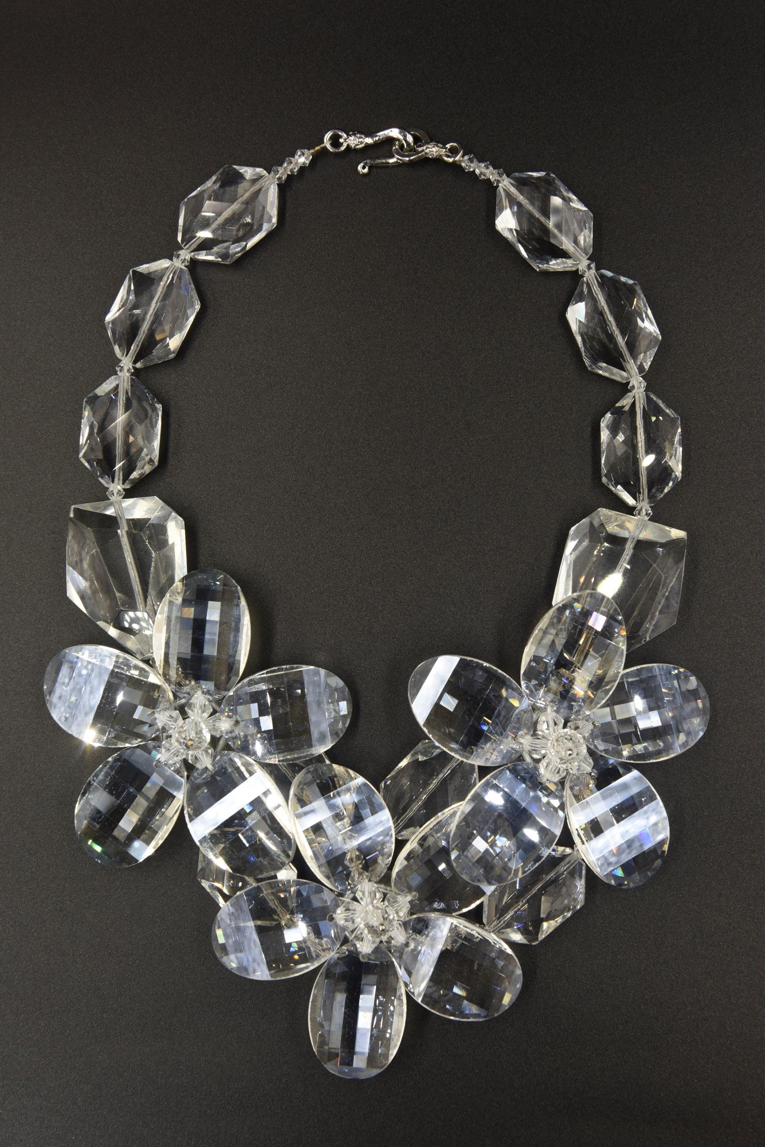 Impressive facetted lucite necklace featuring three large 5 - petal flowers in the center strung on large faceted clear lucite beads.  The back has a hook and eye closure.