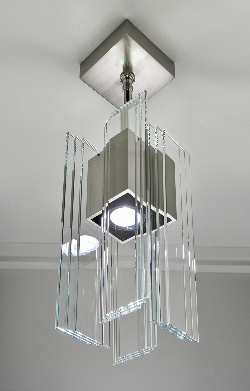 Designed and created by Sidney Hutter glass and light, this pendant has an ultra contemporary style that looks good in any environment. The pendant is created by laminating clear glass pieces using UV adhesive to the nickel plated aluminum housing.