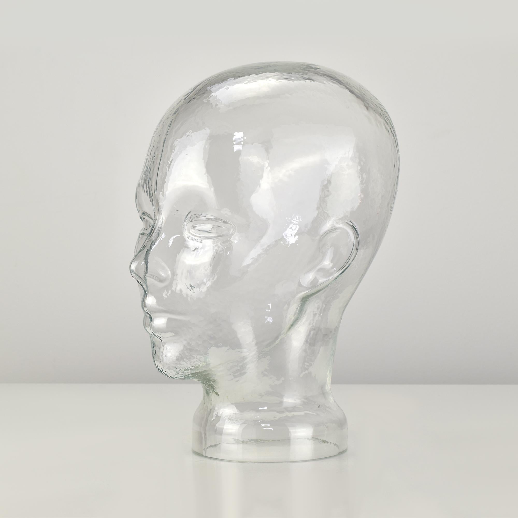 This life-size clear glass head sculpture offers a timeless and versatile design, handcrafted in Germany during the 1970s. Featuring a slightly textured surface, it reflects light beautifully, adding a unique visual effect. Ideal for use as a