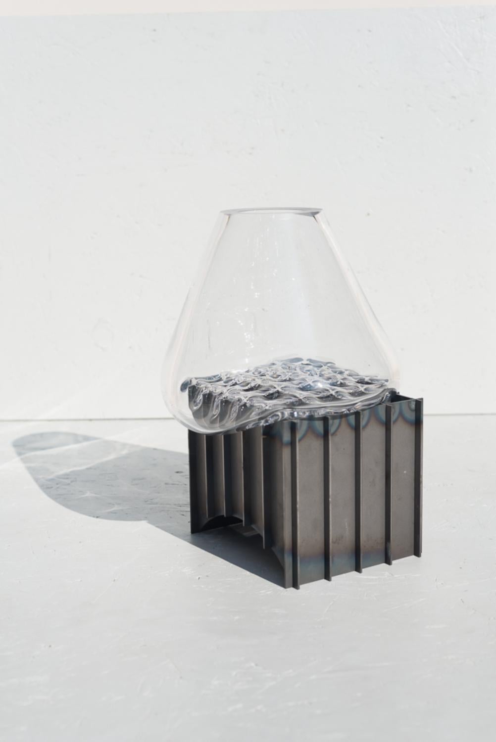 Clear grid table vase by Studio Thier & van Daalen
Dimensions: W 30 x D 30 x H 35cm
Materials: Steel, glass

The studio was keen to find a way to display the fluidity of glass. Therefore they sought the contrast between the industrial steel and