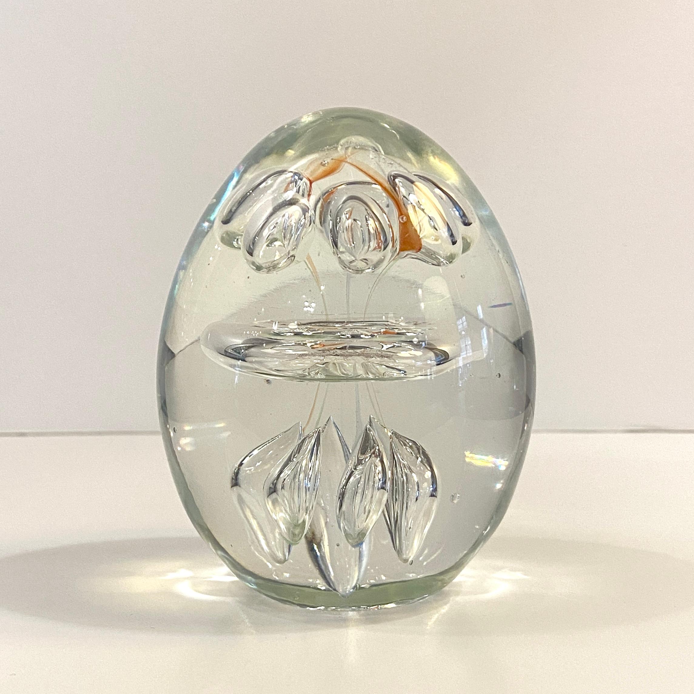 Hand-blown, clear, oblong, art glass paperweight features a clear hand-blown center ring with several controlled bubbles atop and below with the faintest hints of orange dash around the top. Attributed as Italian art glass from Murano, Italy. It's a