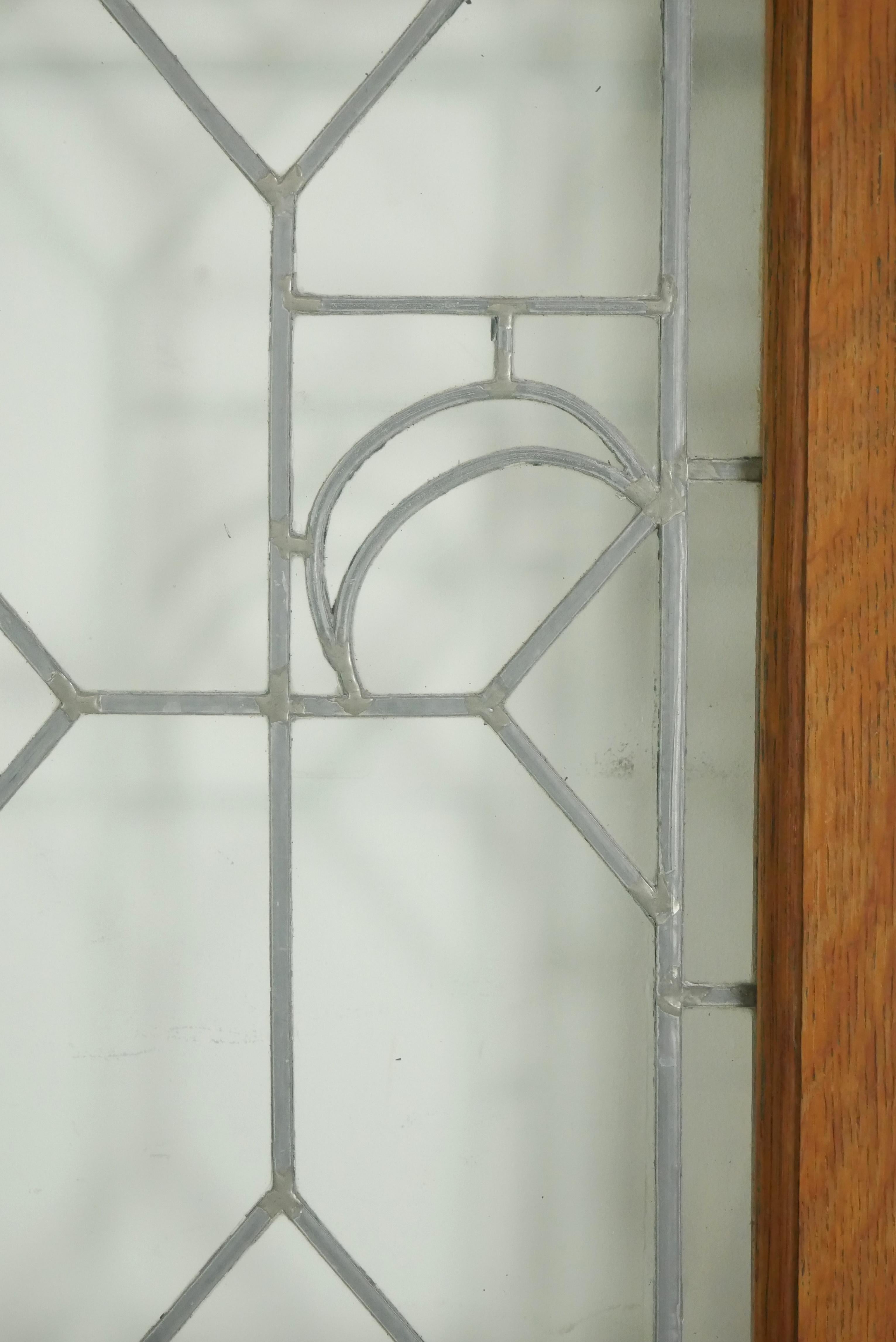Pair of passage double doors with clear leaded glass in a geometric pattern and dark wood tone oak frames. There is some wear on the edges and inner sides. Priced as a double. Some original steel hardware is still attached. Ask about our large