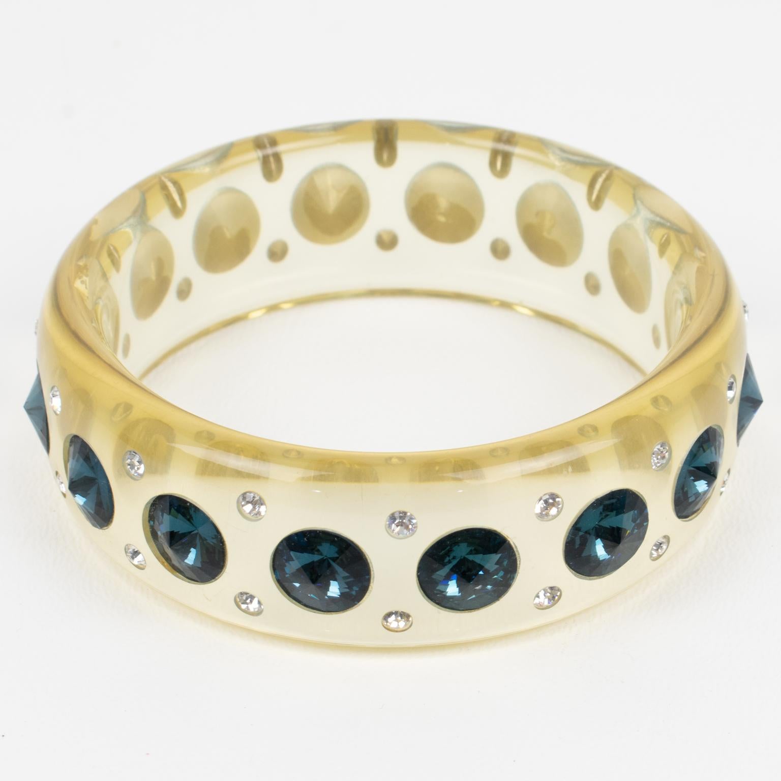 This superb Lucite bracelet bangle features a domed shape in a transparent pale yellow color. The bangle is ornate with massive denim blue crystal rhinestones and tiny silver ones. There is no visible maker's mark.
Measurements: Inside across is