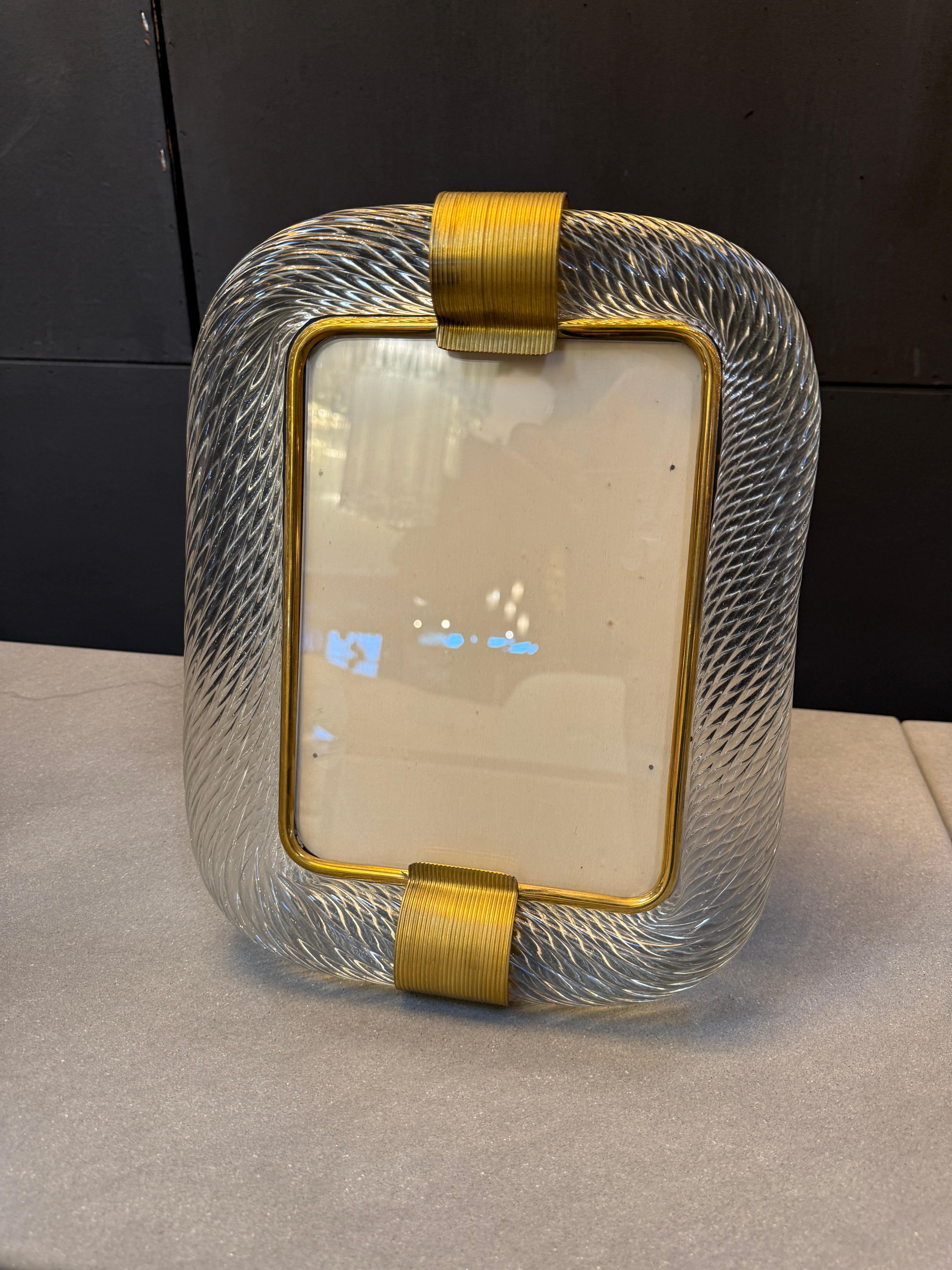 An elegant Italian picture frame from the mid-20th century, crafted in handblown Murano glass with a delicately twisted, textured surface that captures and refracts light. The clear glass is shaped into a rounded rectangular form and accented with