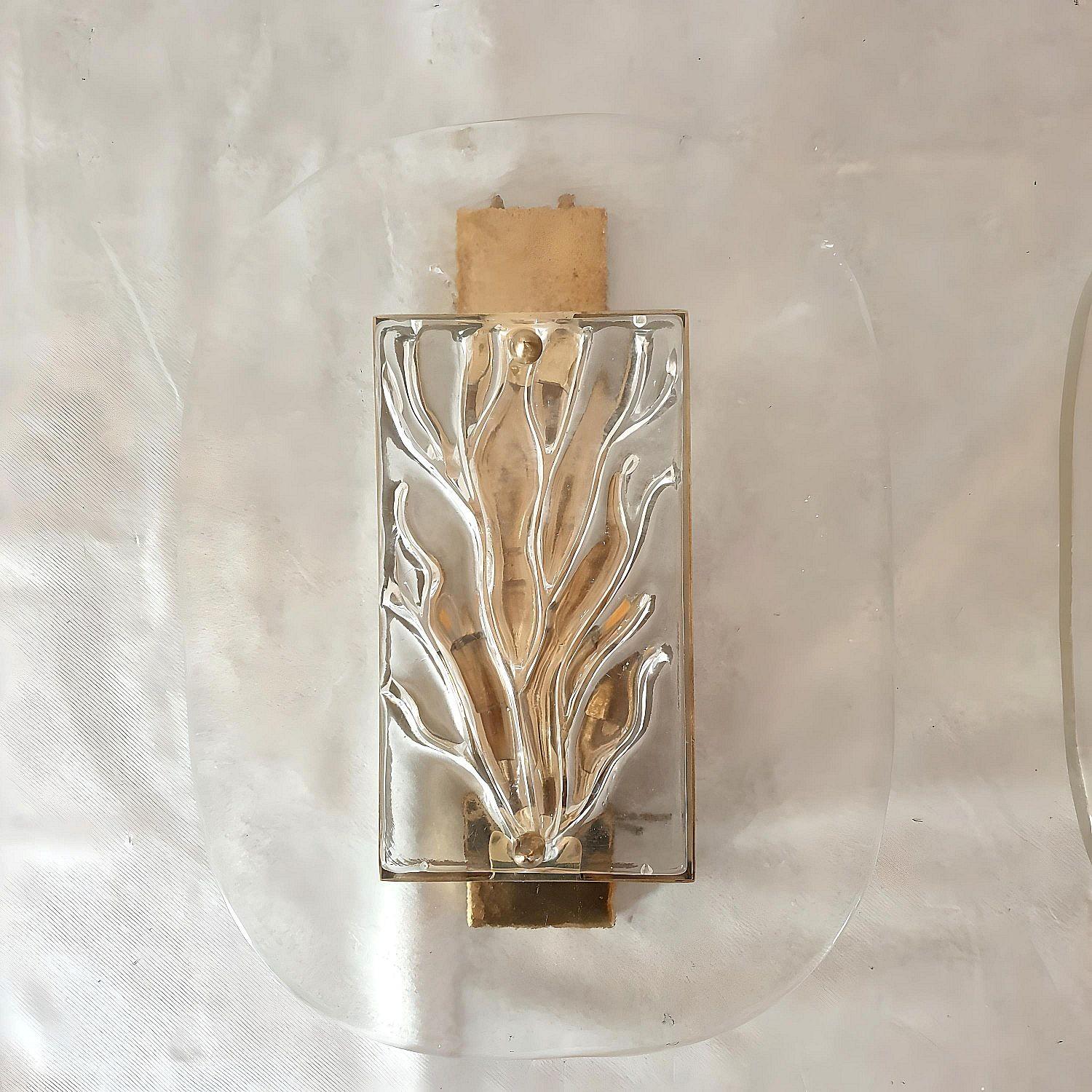 Coppia di grandi appliques in vetro di Murano della metà del secolo scorso, Italia, anni '70.
La coppia di appliques italiane è composta da una struttura in ottone e da spessi elementi in vetro trasparente di Murano.
Il decoro centrale in vetro di