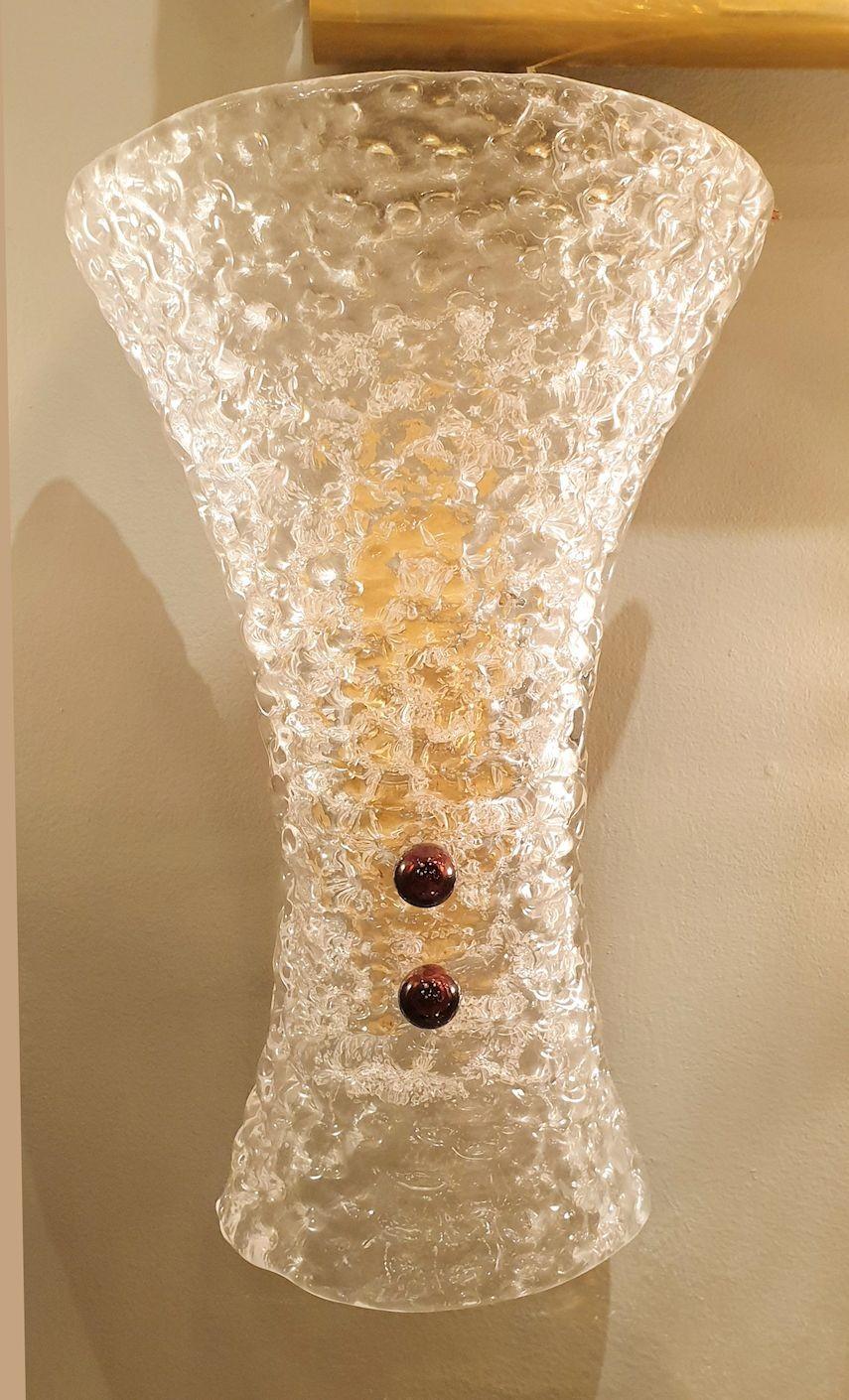 Pair of Murano glass and brass Mid Century Modern wall sconces.
Beautiful quality, in the style of Barovier & Toso. Italy 1970s.
Made of textured translucent clear Murano glass, with 2 purple glass screws each, and brass mounts.
The vintage Murano