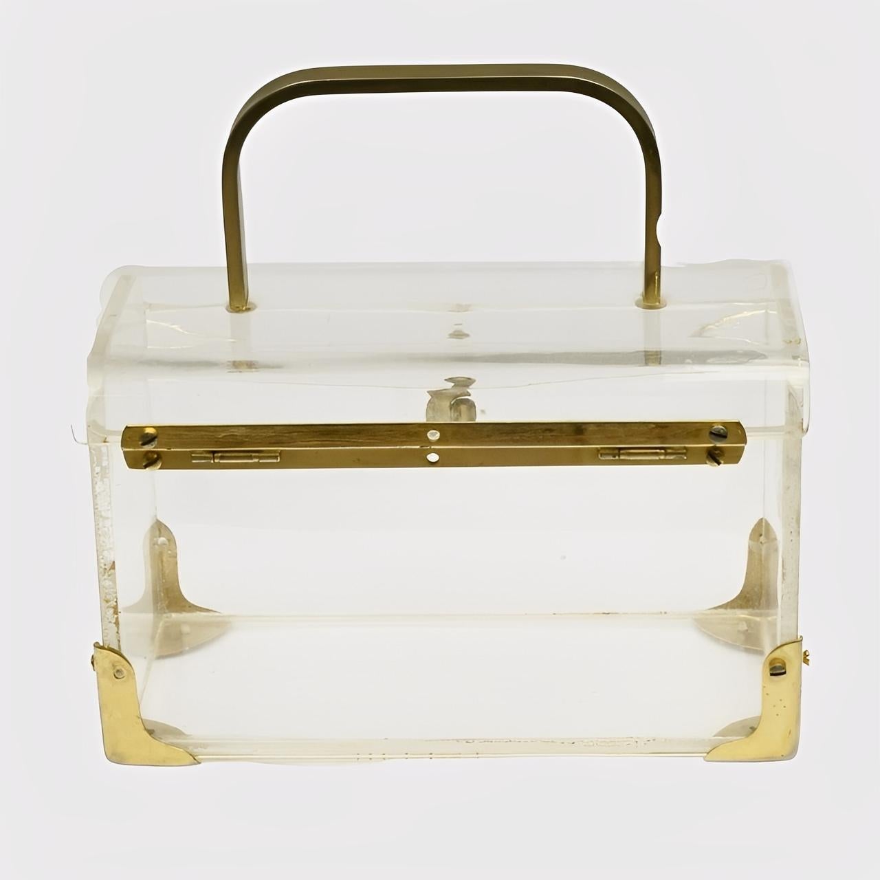Maravilloso bolso de plexiglás transparente, con accesorios chapados en oro.

Mide 16,3 cm de largo por 7,7 cm de ancho y 6,9 cm de alto.

La bolsa tiene arañazos, como es de esperar, y el chapado en oro tiene desgaste. Los herrajes funcionan bien.