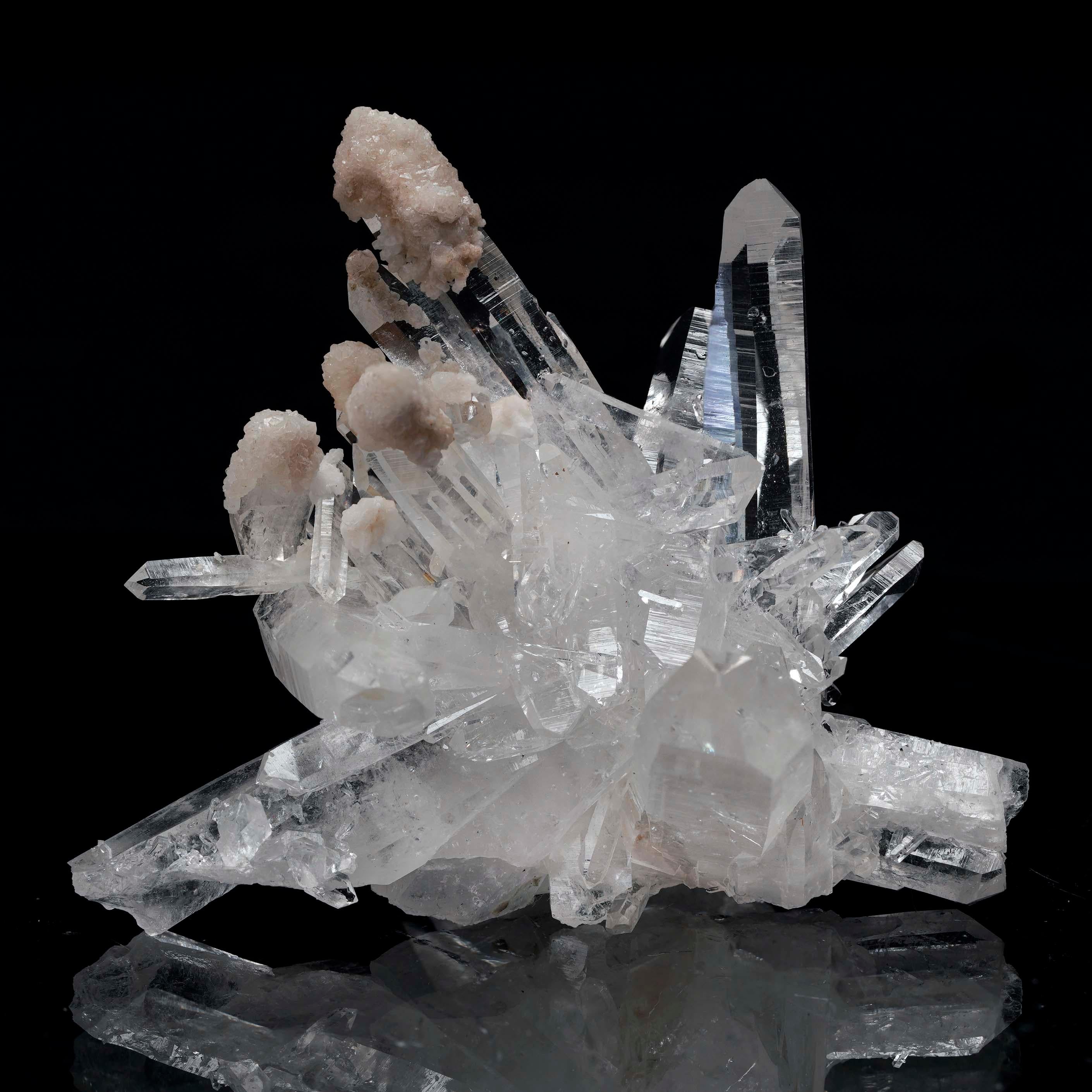 Questo squisito gruppo di quarzo chiaro mostra punte di cristallo nitide e incontaminate, ornate da formazioni di calcedonio morbide e arrotondate. Il calcedonio bianco, liscio e cremoso, aggiunge un contrasto accattivante alla brillantezza