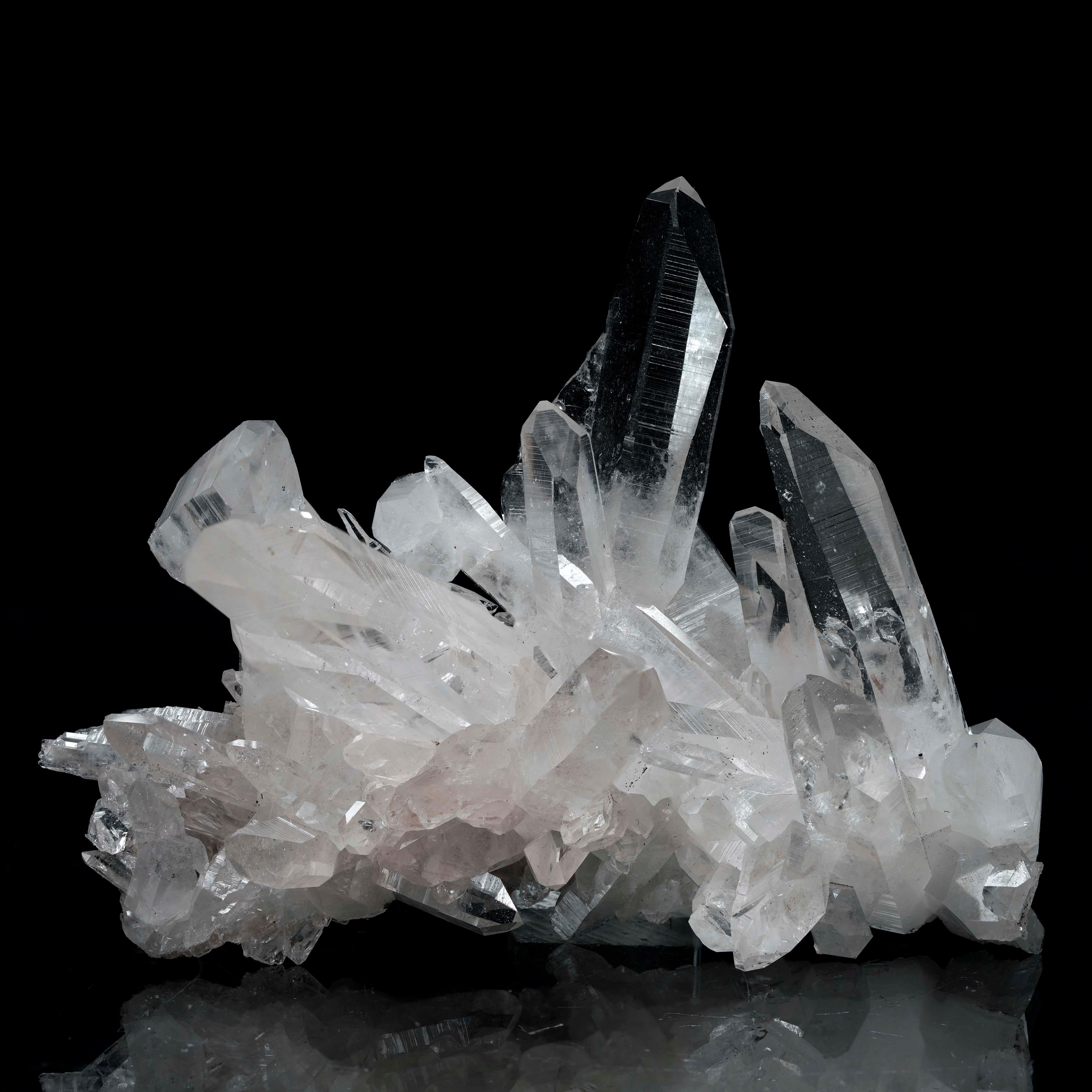 Questo squisito esemplare di quarzo chiaro proveniente dalla Colombia presenta rare inclusioni microscopiche di una varietà rosa di dumortierite, che gli conferisce una sottile e incantevole tonalità arrossata. Le suggestive punte di cristallo si
