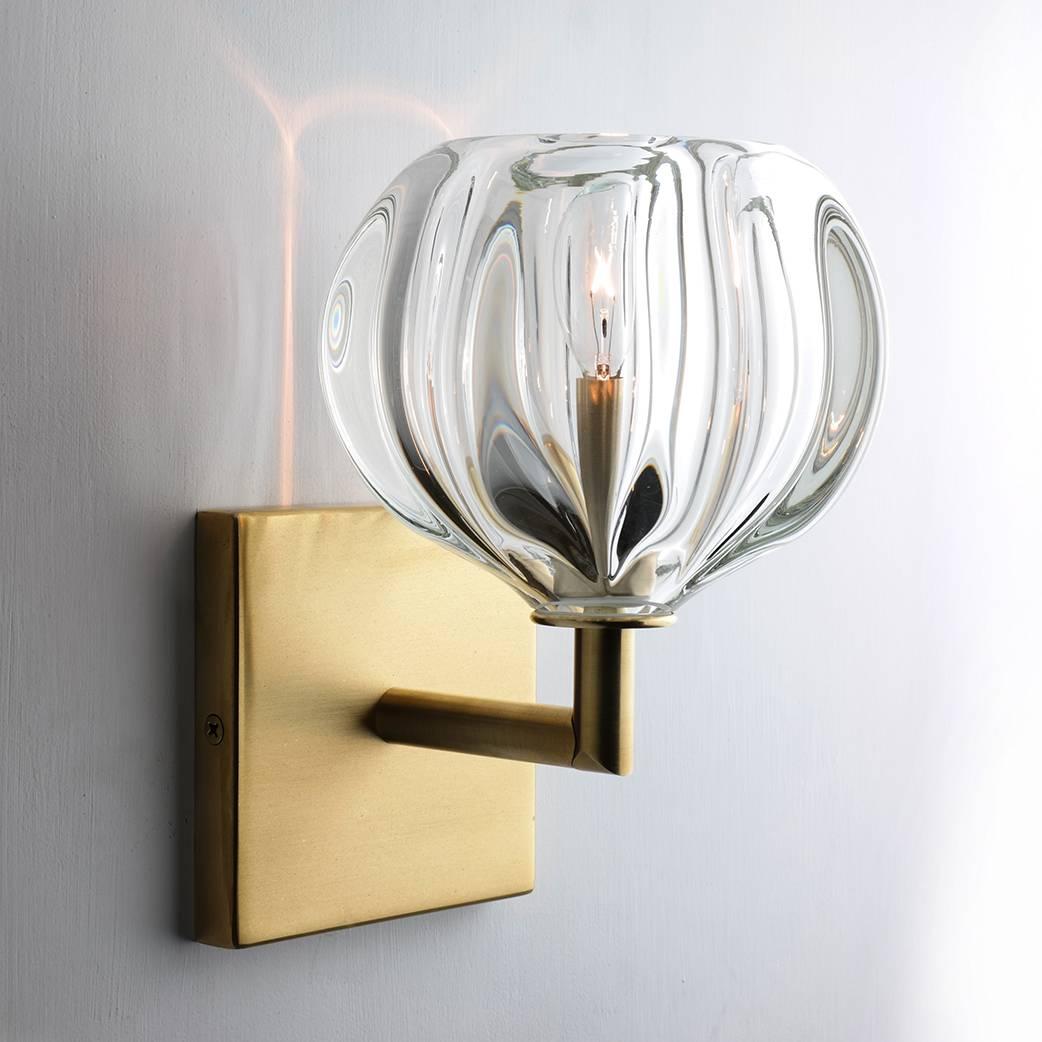 This series of wall sconces is classically inspired. Scaled versions of our pendants extend from elegant metal armatures. The proximity of the glass to the wall allows for each piece’s unique light pattern to be magnified. Hand blown and shaped in