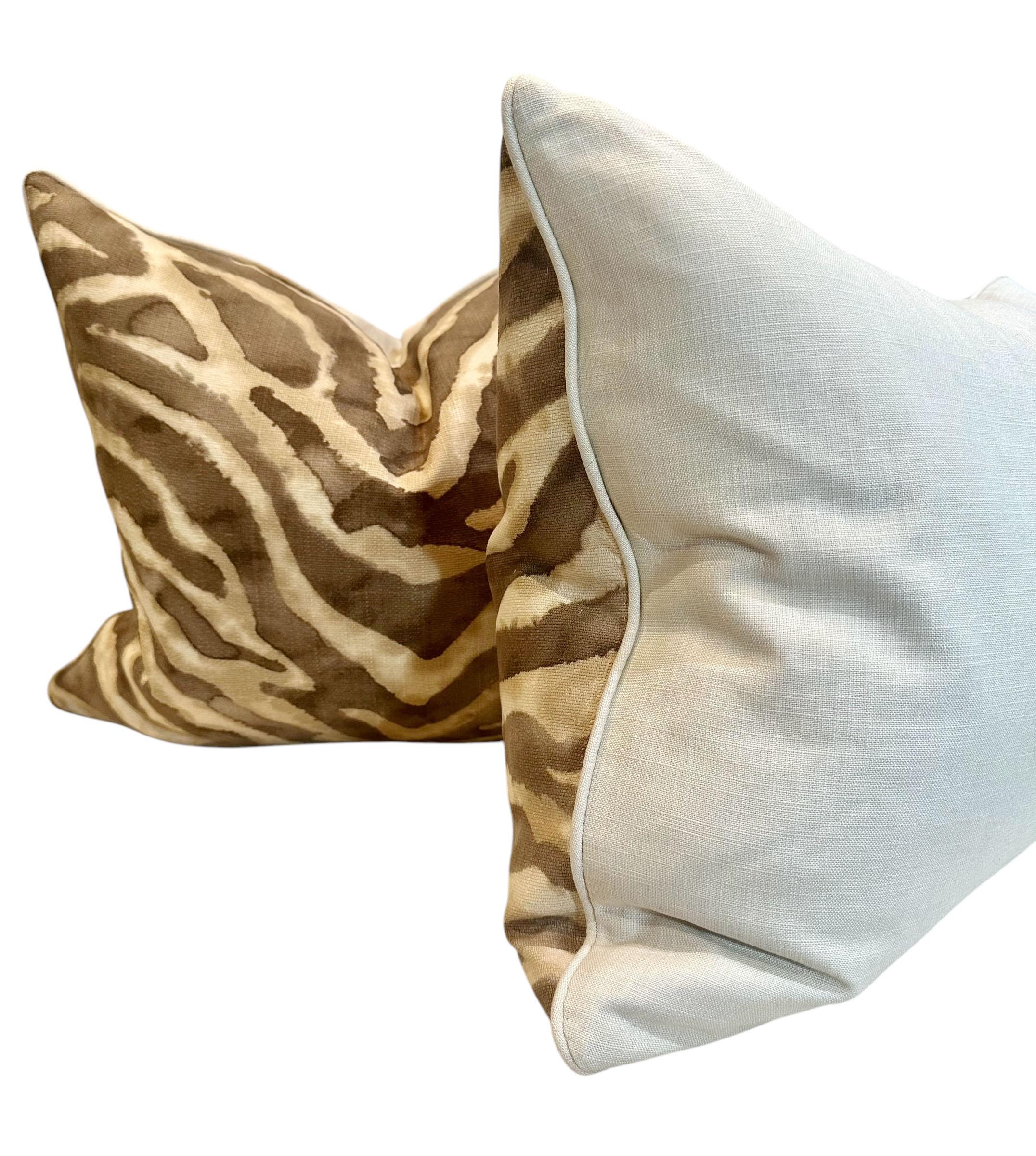 A pair of old clearance house fabric zebra pillows circa 1970s with white linen Scalamandre on the backs. They are stuffed with down and goose and have a zipper. They are all linen and piped in the beige linen. 