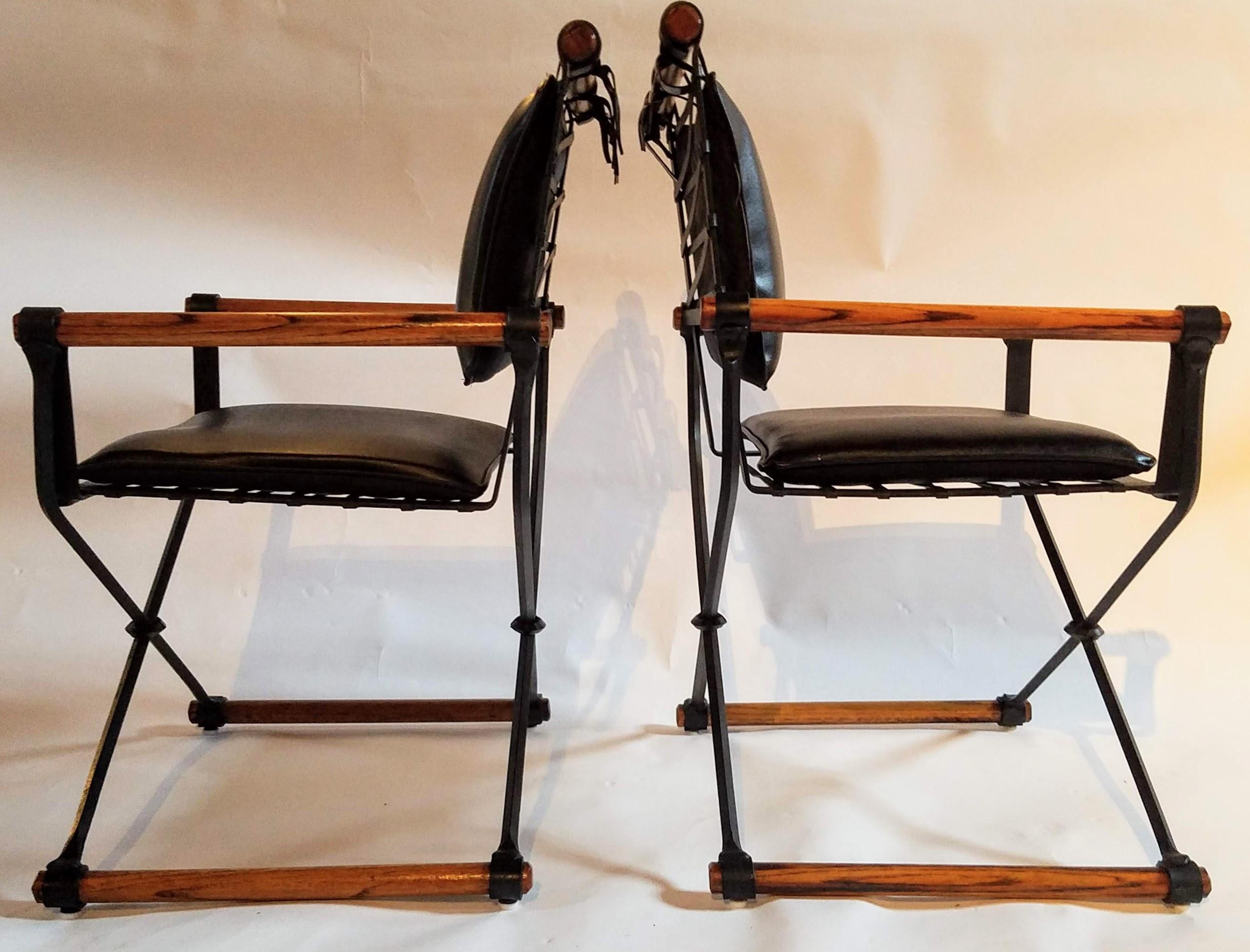 Cleo Baldon pair of handcrafted Campaign chairs from her contract line manufactured by Terra in the mid-1960s thru the mid-1970s.
The wrought iron chairs are lacquered in their original black color with fumed oak rods and bridle ties on the back