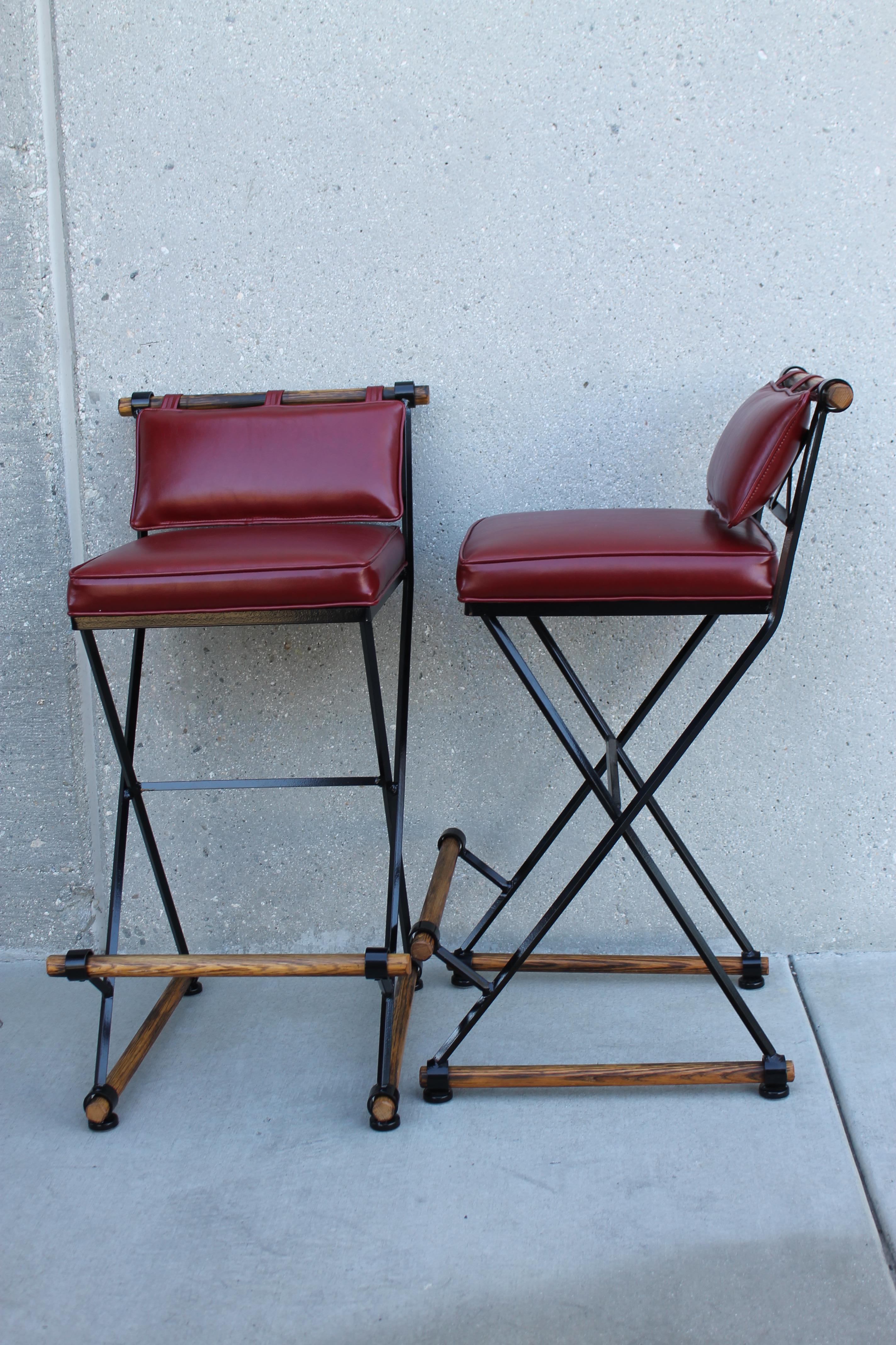 Pair of barstools in the style of Cleo Baldon and manufactured by Terra Furniture. We sand blasted and powder coated them to their original black color. We had new recycled burgundy leather cushions made with bridle ties. Stools are steel, oak and