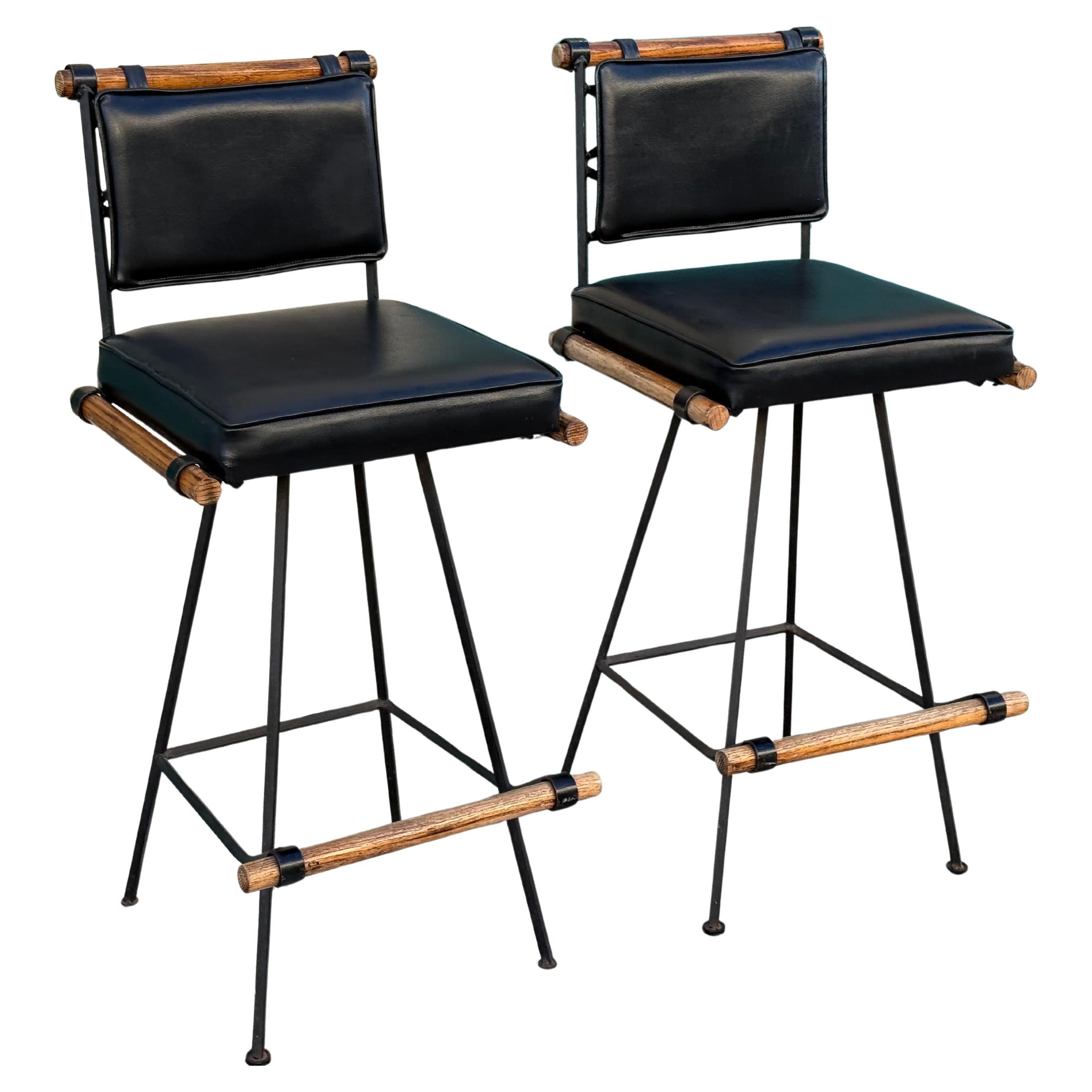 A pair of classic mid-century black leather swivel bar stools for Inca Products, USA, circa 1960s in the style of the legendary Cleo Baldon. 

Price is for the pair.

This vintage pair feature wrought iron frame with lattice seat backs and brown