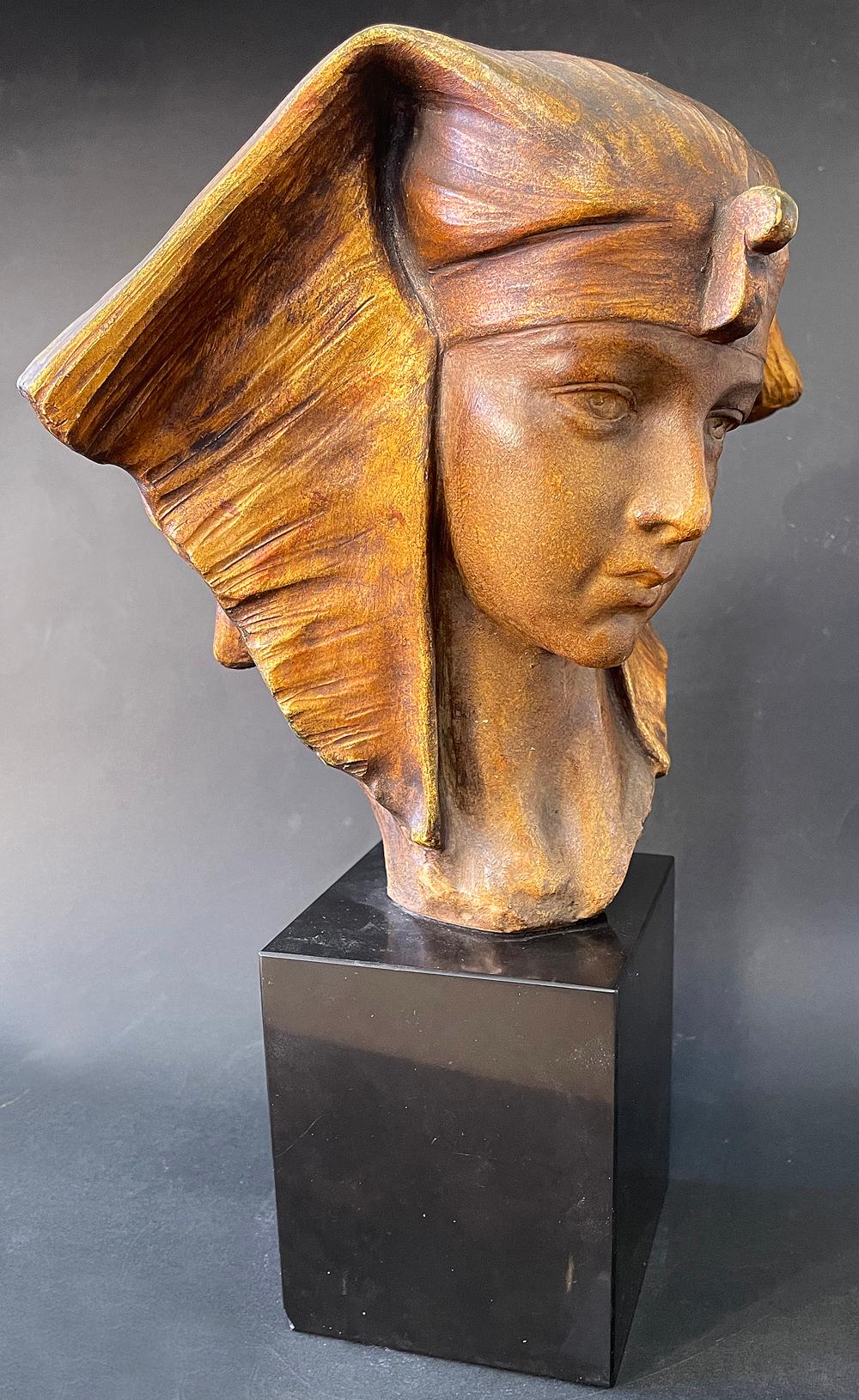 Extremely rare and breathtaking, this gilded Art Deco terracotta sculpture depicts Cleopatra as a young woman with beautiful, fine features and a thoughtful, pensive appearance, crowned with a headdress that flares to either side of her head and is