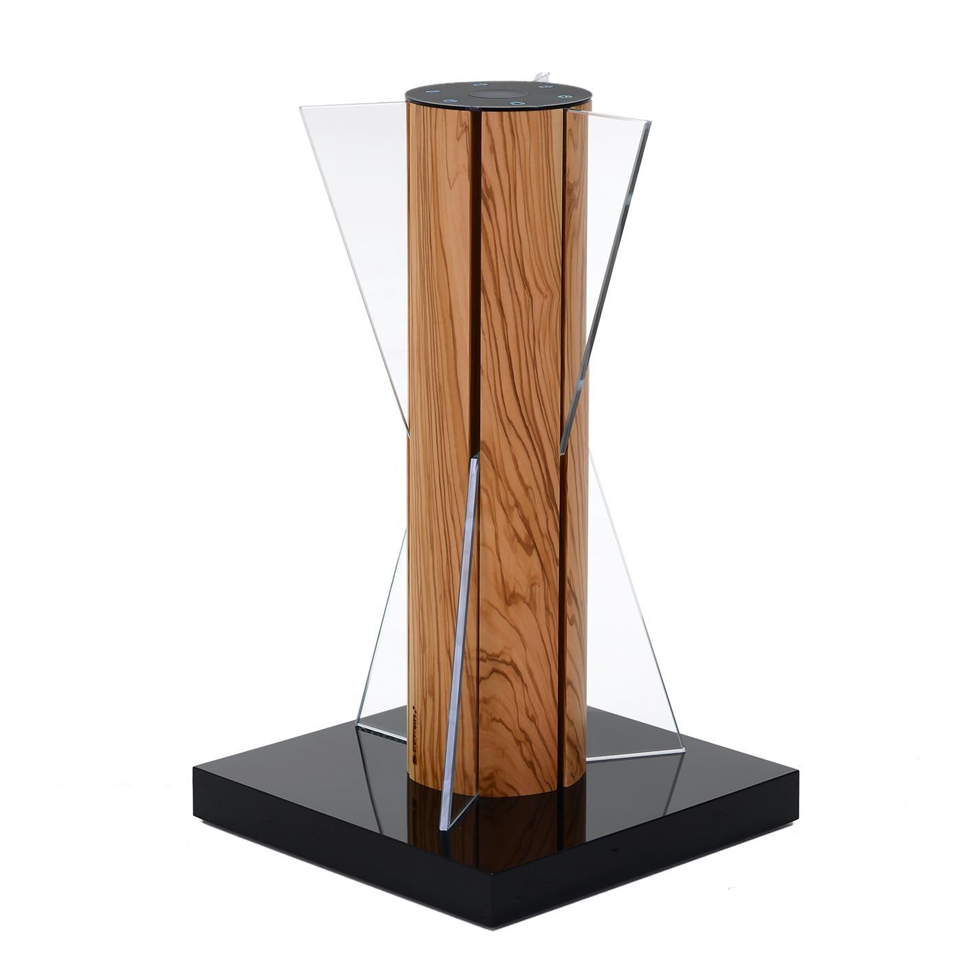 The silhouette of this extremely modern table lamp evokes an hourglass, the ancient, absolute symbol of time that has been into integrated into an olive tree, the symbol of the centuries. This item is part of the company's Carpentry collection. Made