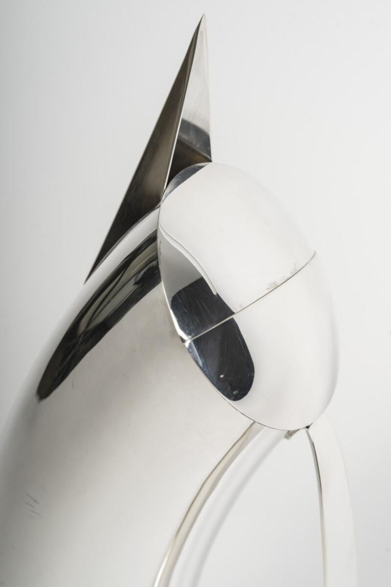 Brocca in argento massiccio di forma cilindrica ricurva, con beccuccio a punta e ampio manico a nastro e coperchio a cerniera. La forma è geometrica, con una linea pura e una struttura moderna. Questo pezzo è il numero 28 di un'edizione limitata di