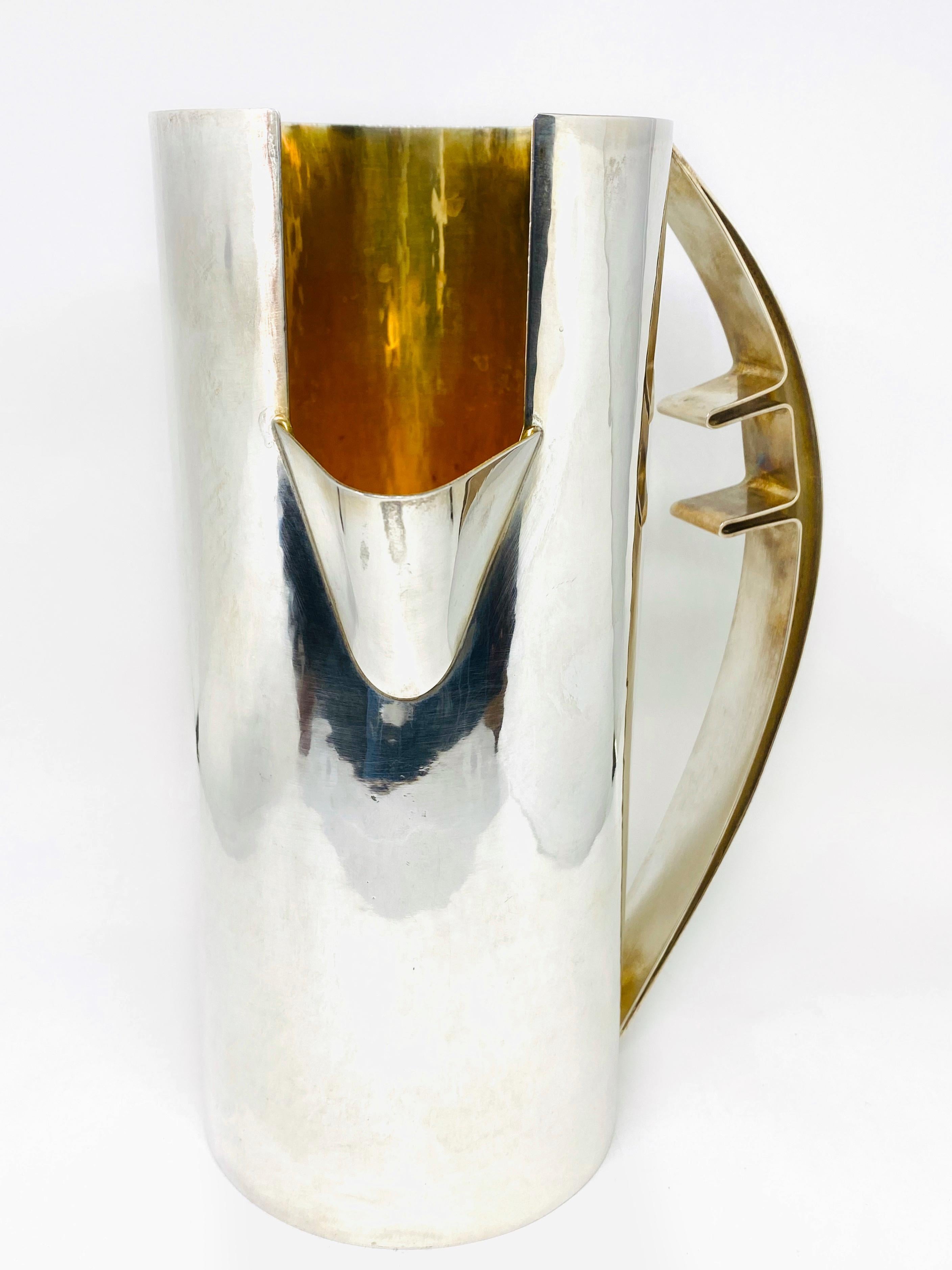 Cleto Munari Silver and Gold Plated Water Pitcher by Carlo Scarpa 

Product details:
Circa 1960's
800 Sterling silver with hammered gold plated overlay interior
Features a large curved handle and a deep set spout for easy pouring
Designed by Carlo
