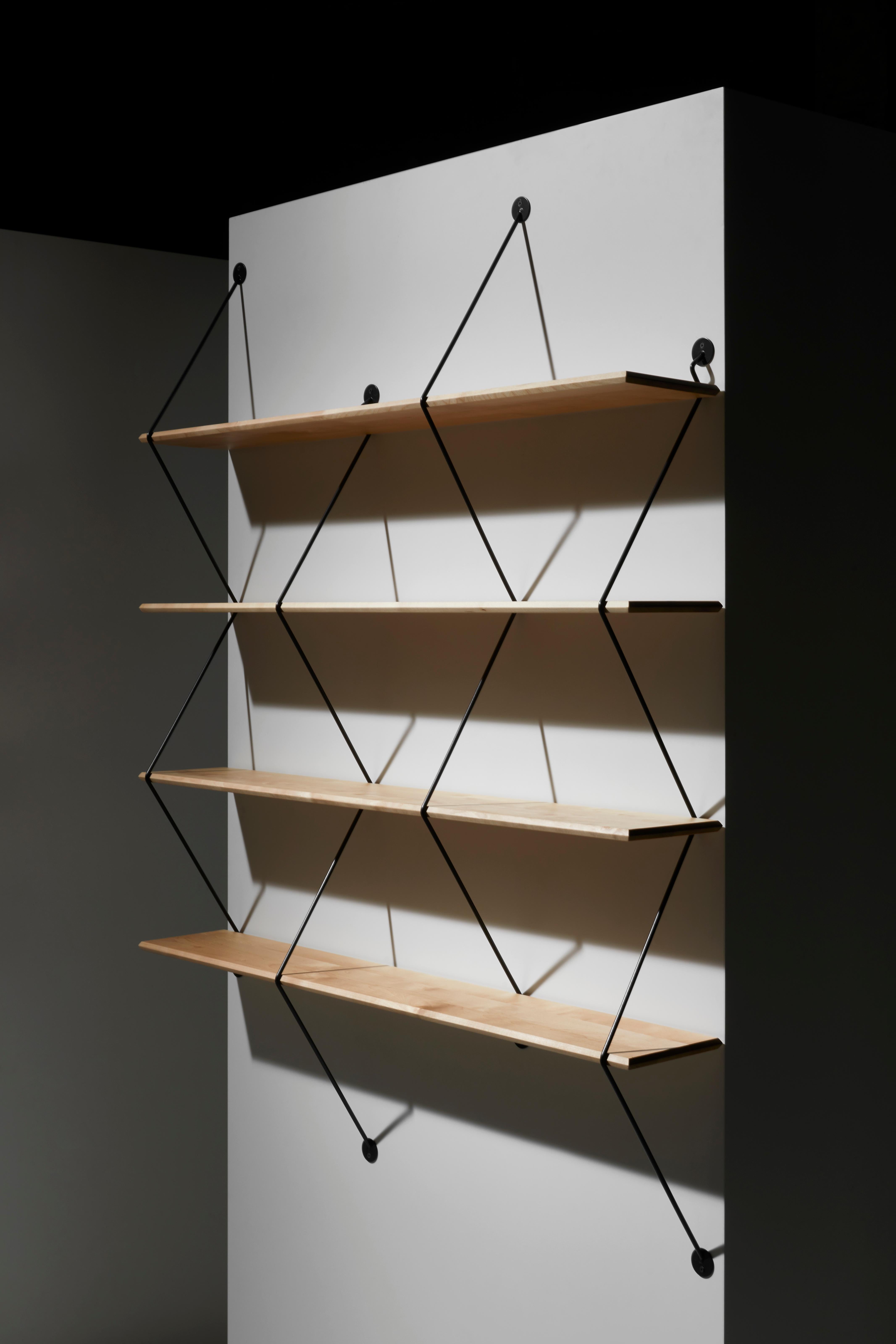 Climb is an ingenious shelving system made of beveled wooden boards supported by metal wires. Measure: 120cm.
The design plays with the sensation of tension of the wires that grasps the wooden shelves and becomes a rigid structure as the product is