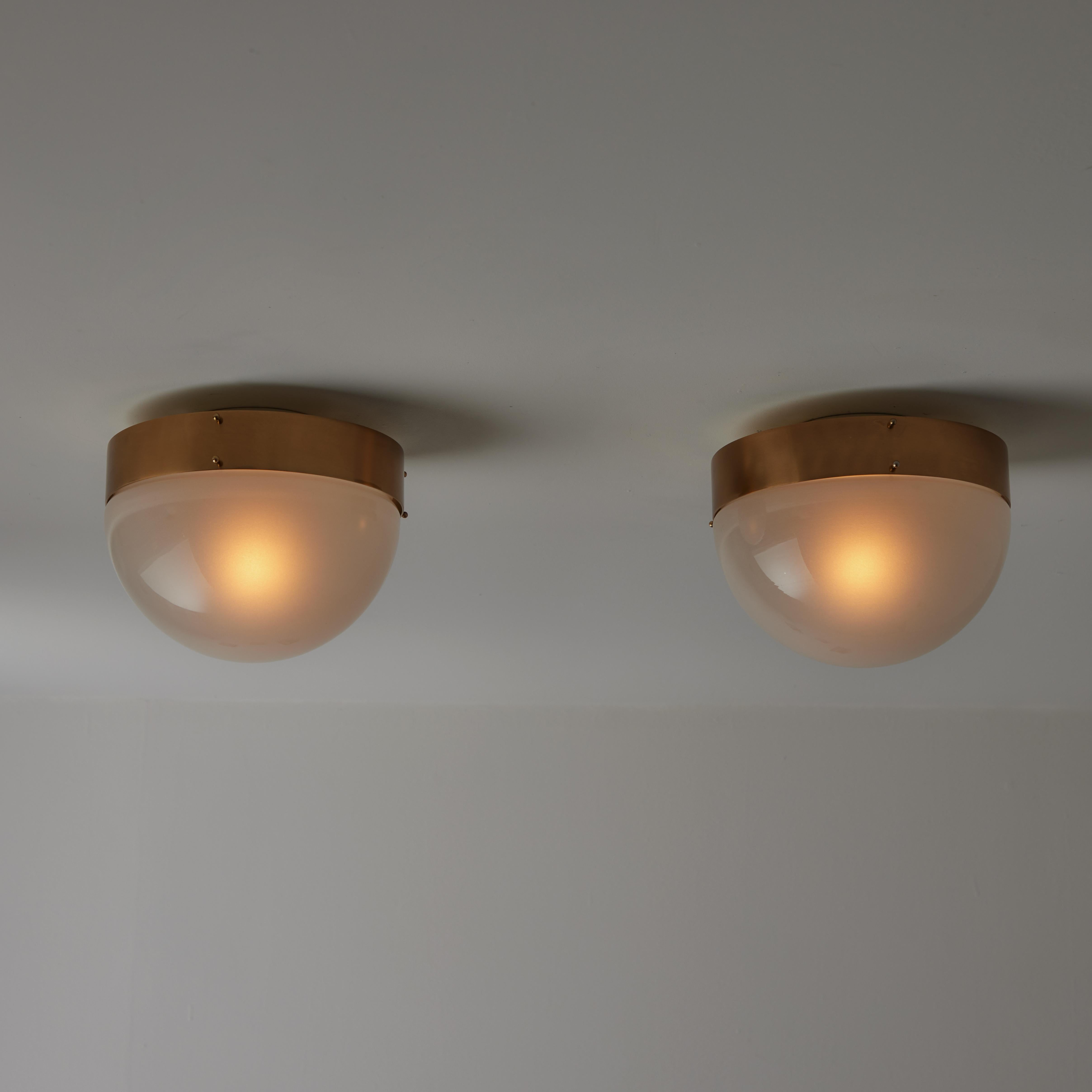 'Demi Clio' flushmounts by Sergio Mazza for Artemide. Designed and manufactured in Italy, circa the 1960s. Clear sandblasted glass diffuser paired with polished aged brass outer ring. Each light holds an E27 socket type, adaptive to the US. Rewired