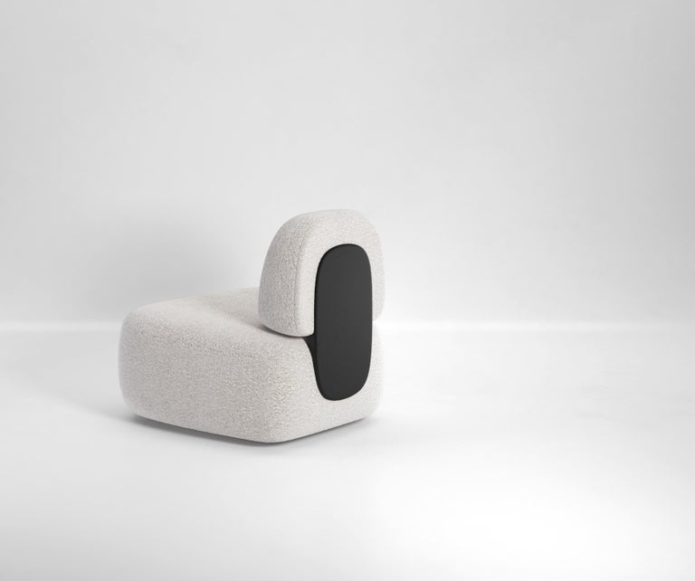 The clip Lounge chair features two upholstered elements, a back and a base, connected by a single, visible piece of wood which sits flush with the two upholstered pieces. It gives the impression that these two elements have been clipped together by