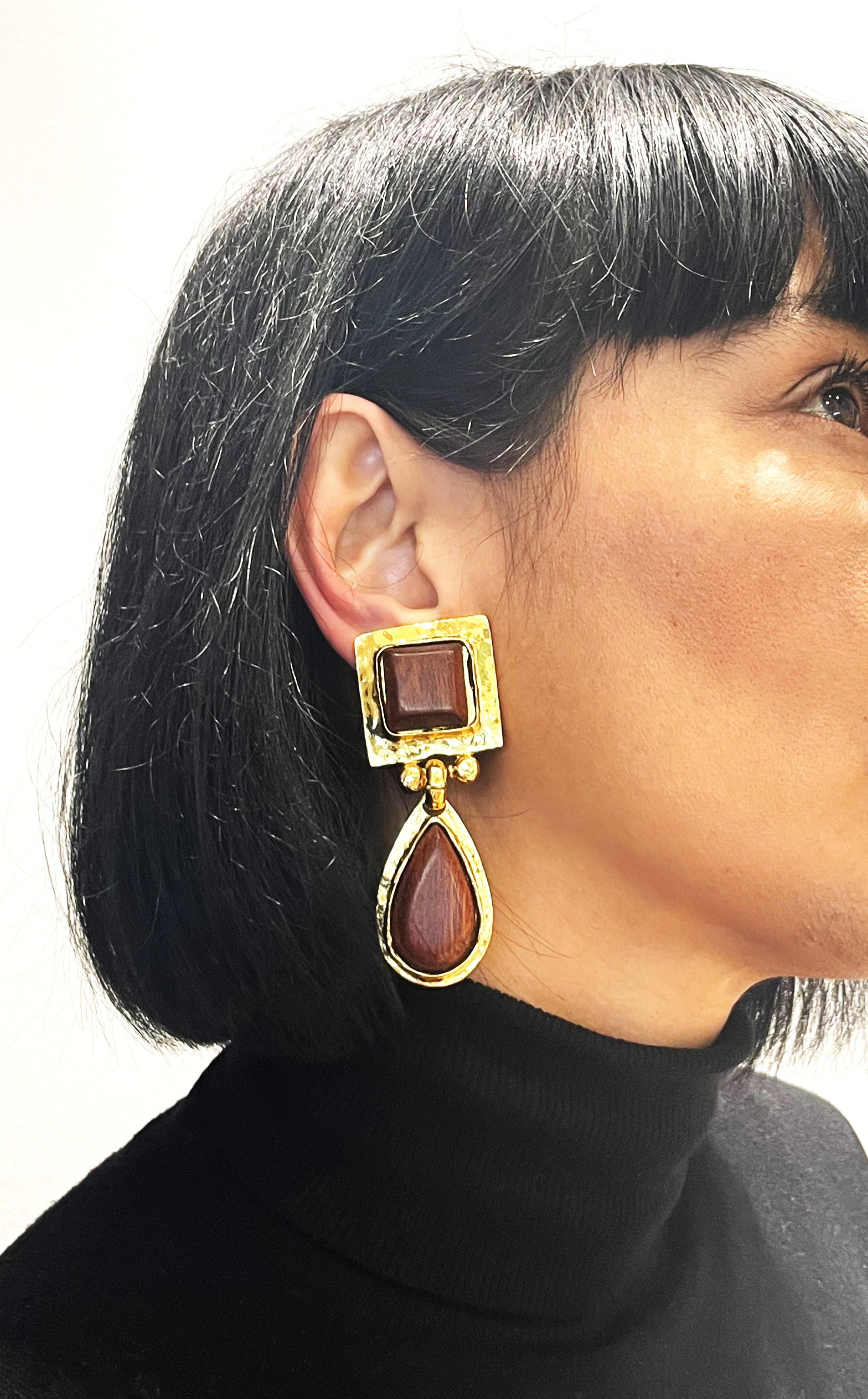 Long decorative ear clips signed Eduard Rambaud Paris consisting of a square gold-plated part with a drop hanging from it. Filled in with brown wood. 

Measurement: Full length 8 cm, upper square part 3 x 3 cm, attached drop 4.5 cm

Features:
-