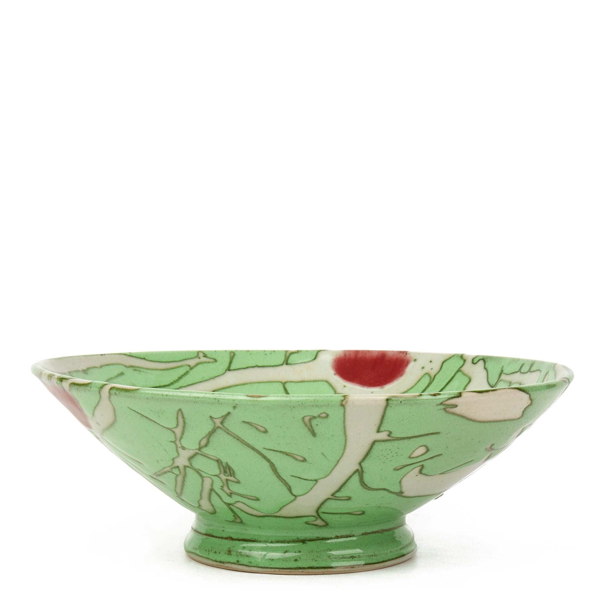 A very stylish studio pottery bowl highly and entirely hand decorated with an abstract patterned design in bright colors in green white and red with black outlines by Norfolk based potter Clive Davis. The bowl has a moulded artist mark incorporated