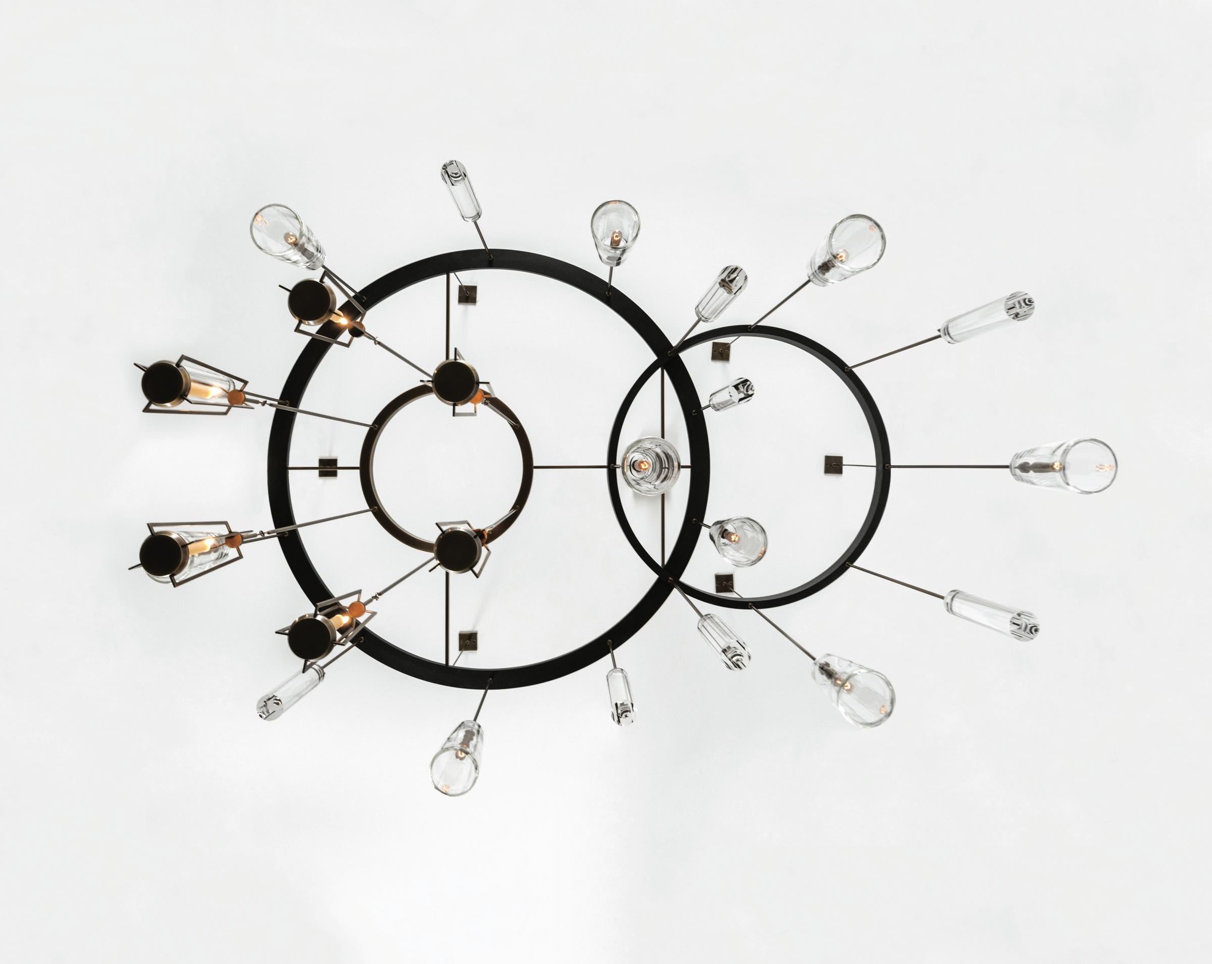 Soft light, precise details
Designed to mimic the intricate gears of a clock, this sculptural chandelier is made of three interlocking bronze and steel rings.
The solid hand-blown crystal weights refract and distort the light, giving viewers a