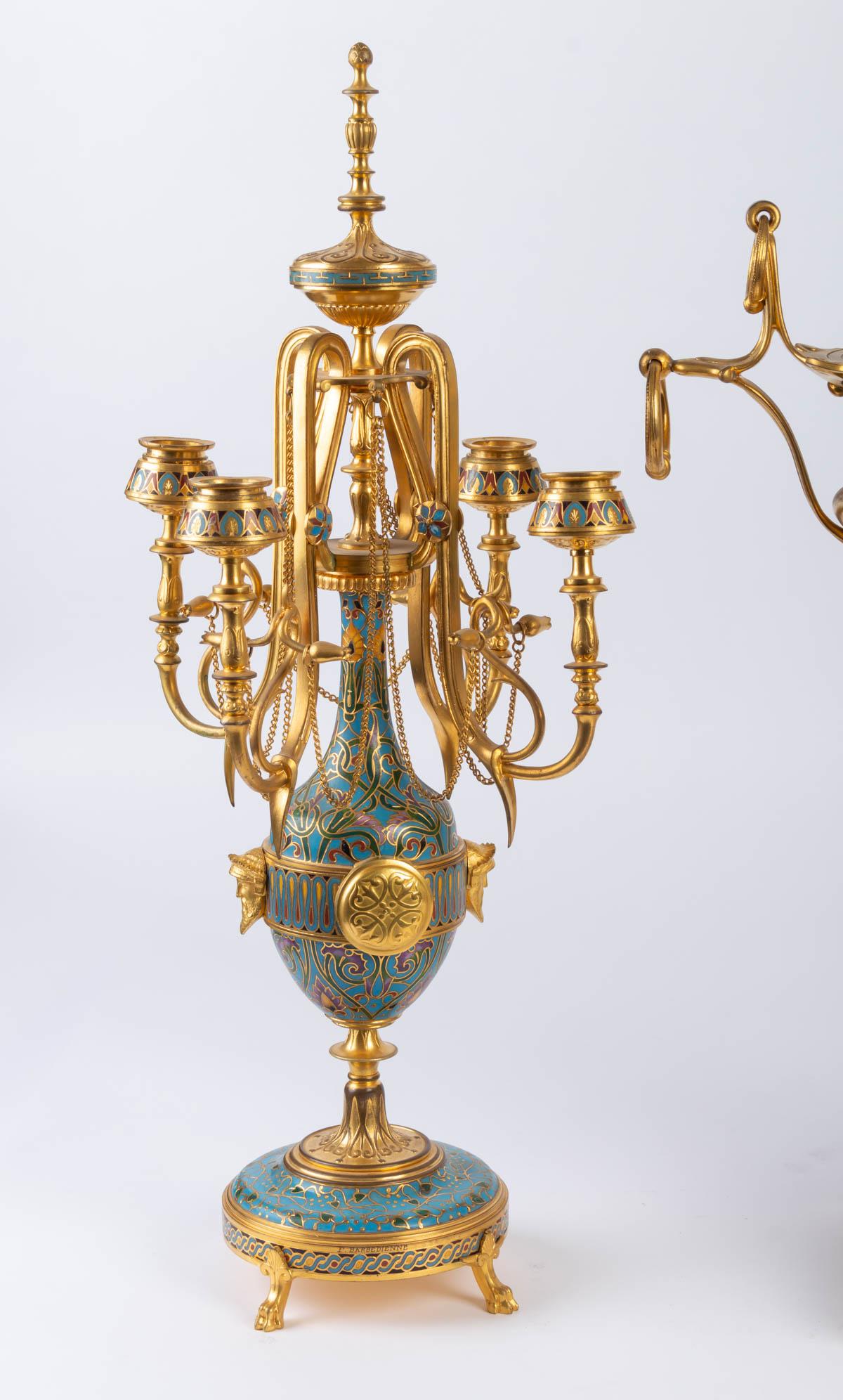 Cloisonné and enamelled bronze set, signed F. Barbedienne, 19th century, Napoleone III period.

The clock surmounted by a gilded bronze bowl and an onyx body.

Measures: Clock H 45 cm, W 39 cm, D 23 cm;

Candelabra H 50 cm, W 25 cm, D 25 cm.