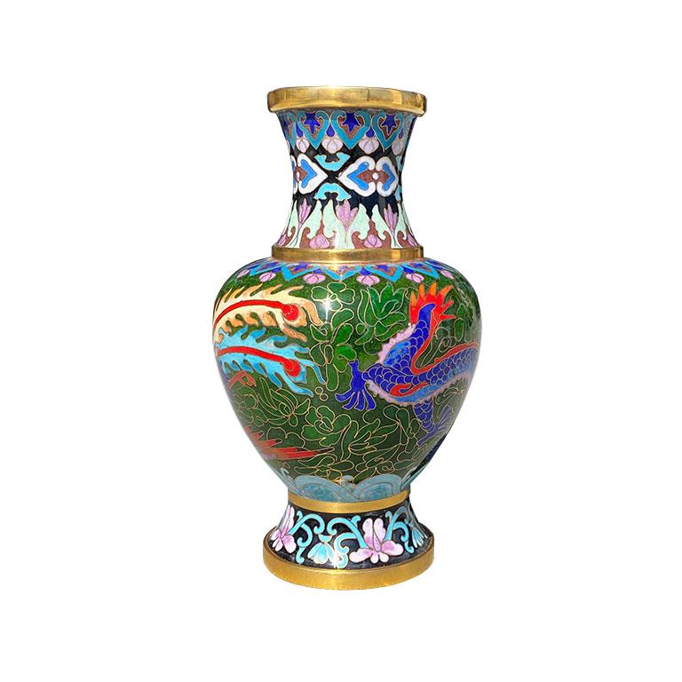 A gorgeous cloisonné vase with an Asian motif. A brightly colored blue dragon decorates the side with purple orchids, stylized blue detail along the sides and bottom, and a brass base and rim. This lovely chinoiserie piece will be great for the